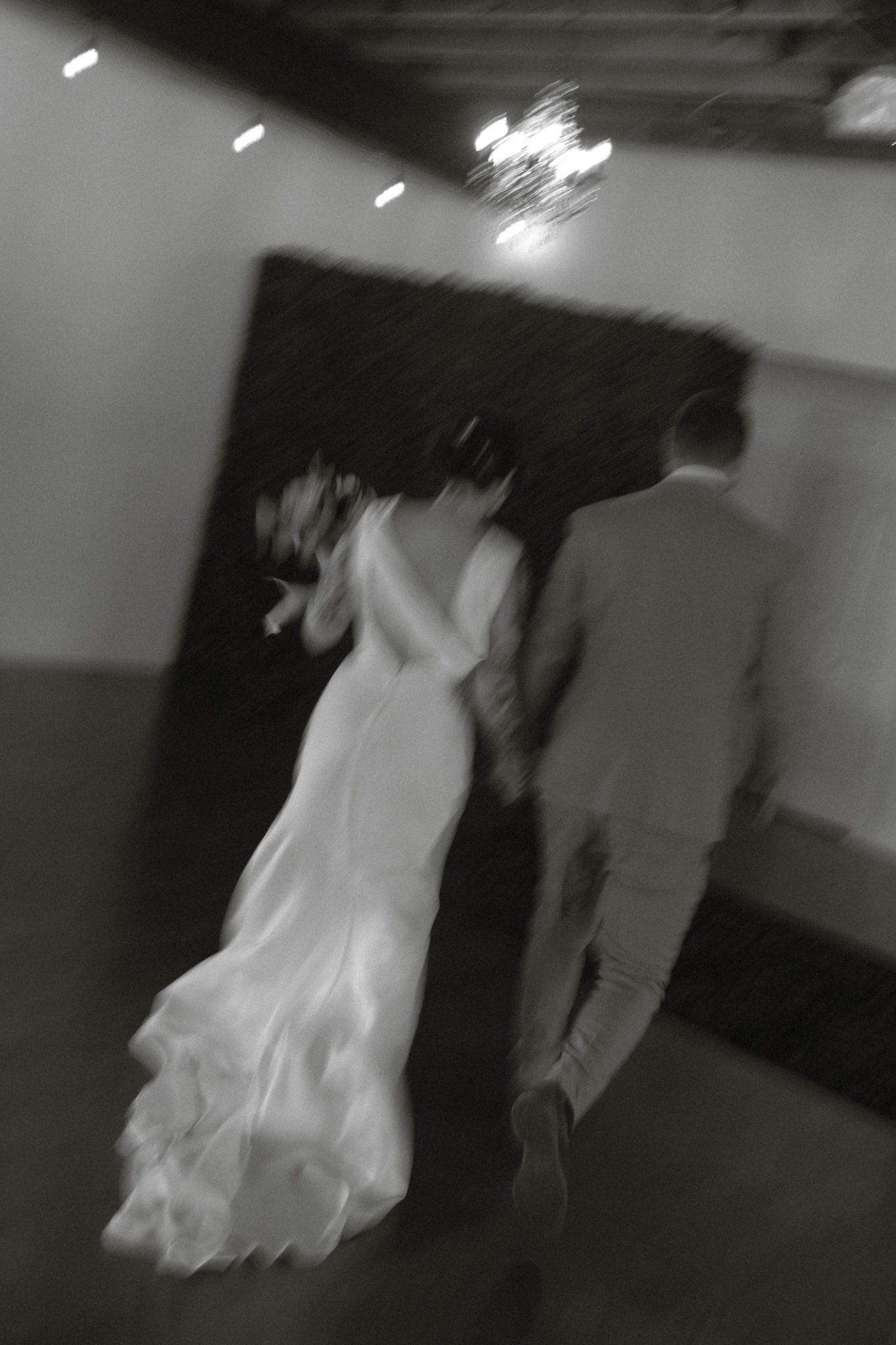 A couple dancing together in a dimly lit space captured in black and white with motion blur effects.