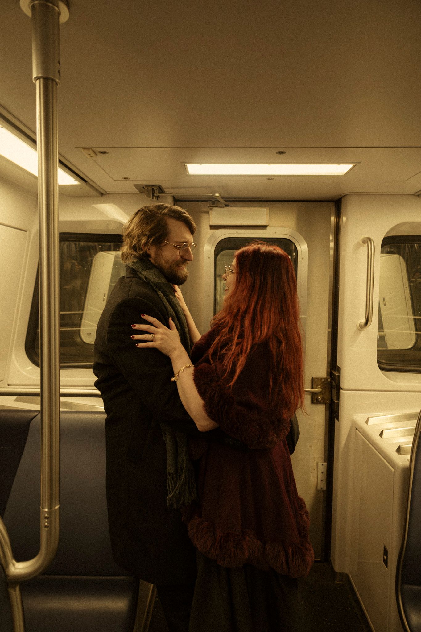A couple embraces passionately in a dimly lit subway car interior.