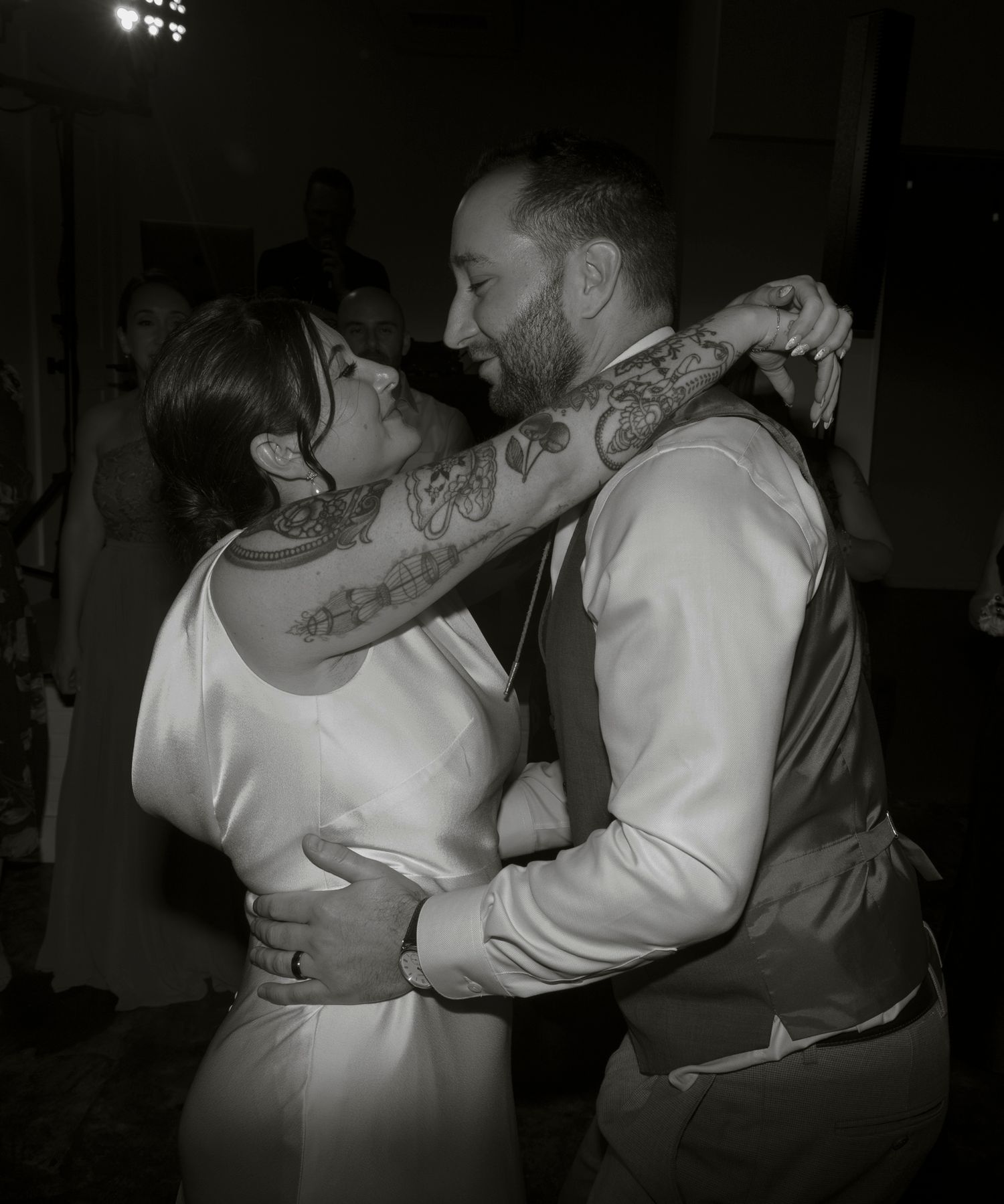 A couple in white clothing dance together in a dimly lit room, shown in a series of black and white photos.