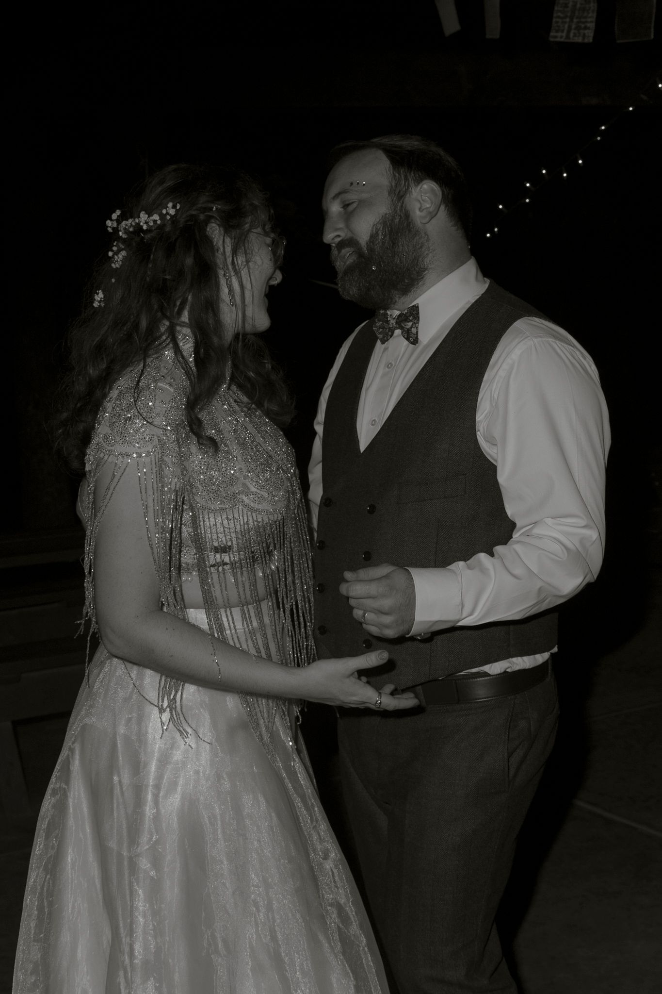 A couple shares a romantic dance together at a wedding reception in a dark venue.