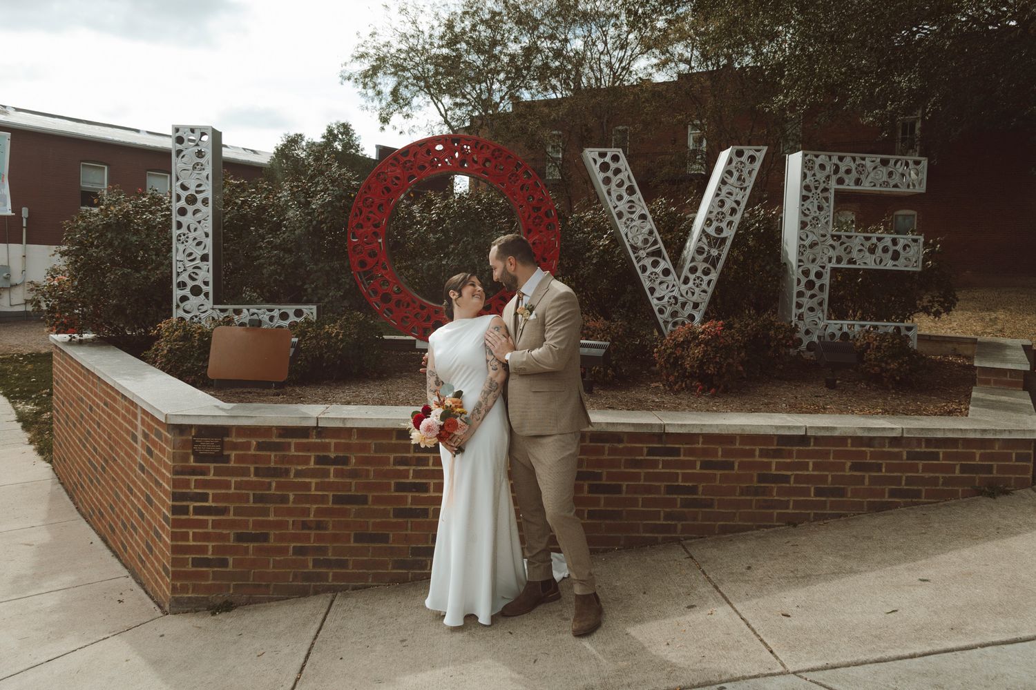 Large decorative LOVE letters displayed outdoors against a brick wall backdrop at a wedding venue.