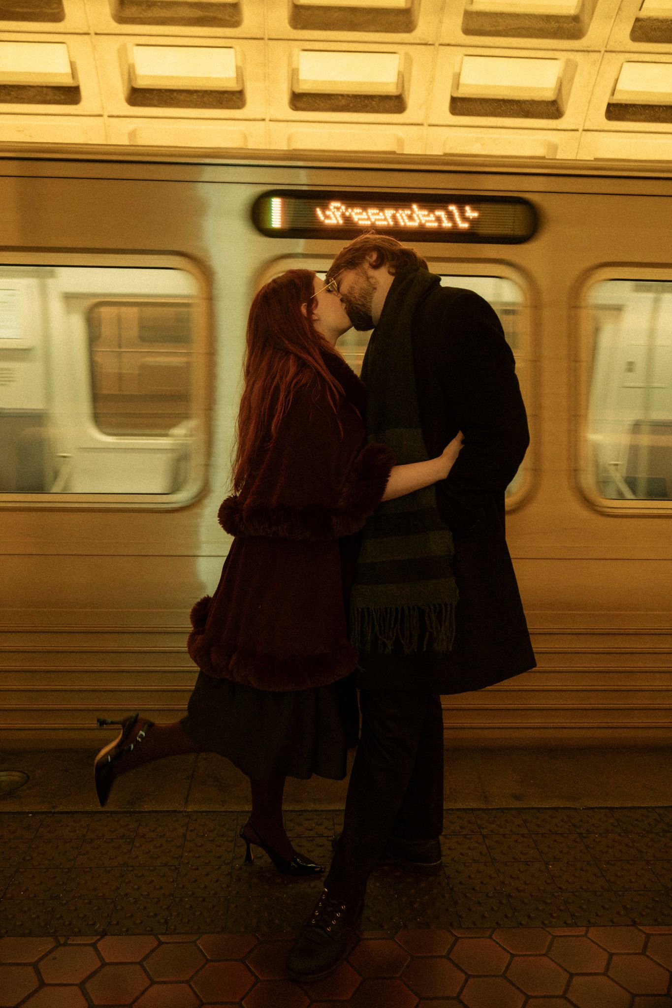 A romantic scene unfolds on a subway platform with warm sepia tones and hexagonal floor tiles.