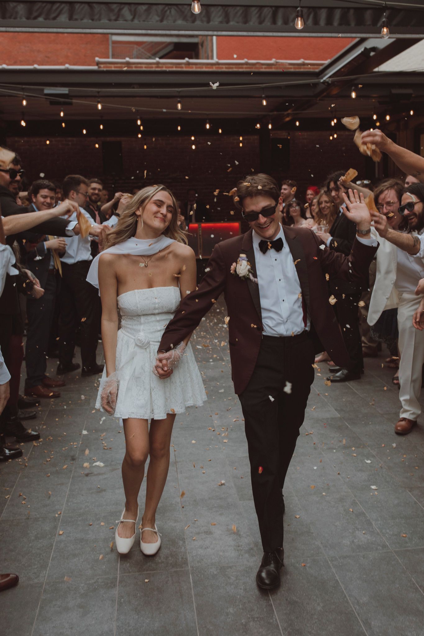 Bride and groom dance together at wedding reception with guests holding sparklers in the background.