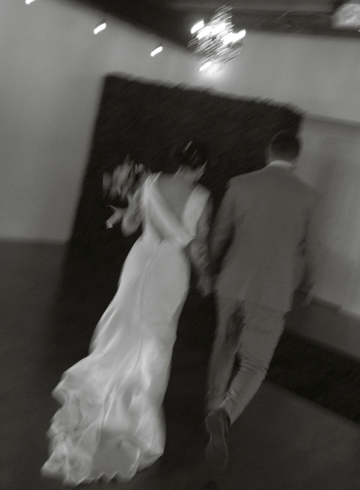 A blurry sequence of black and white security camera footage showing movement in a dark hallway.
