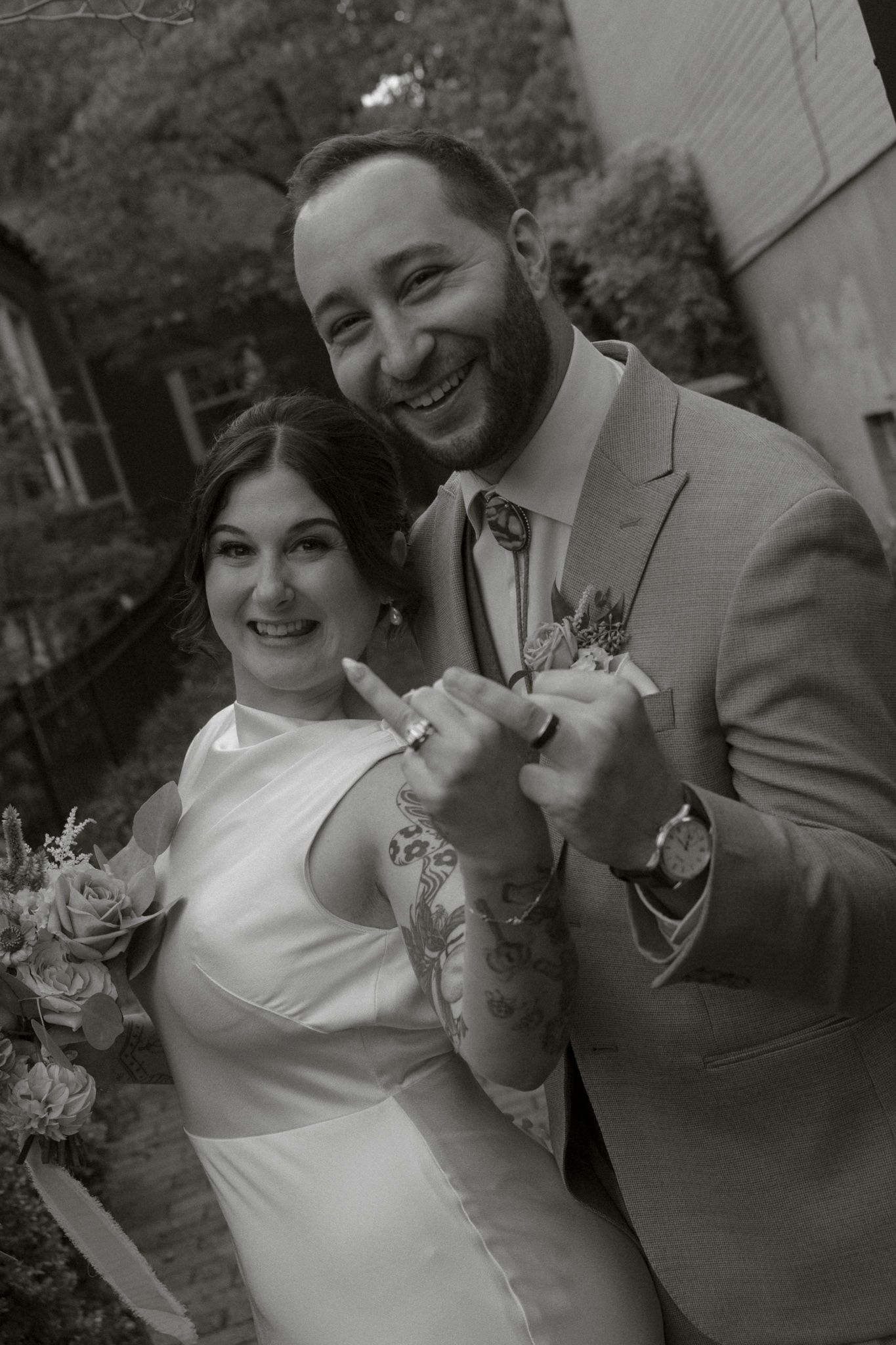Candid black and white portrait of newlyweds sharing a happy moment outdoors.