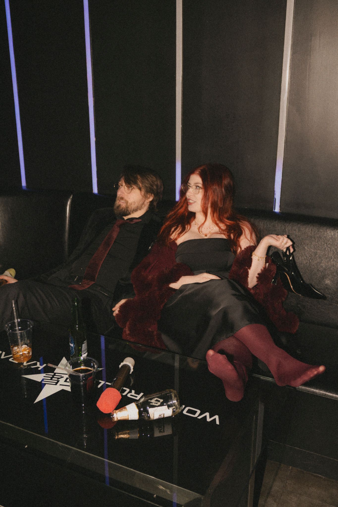 A group of people relaxing on reclining seats in a dark theater or cinema space.