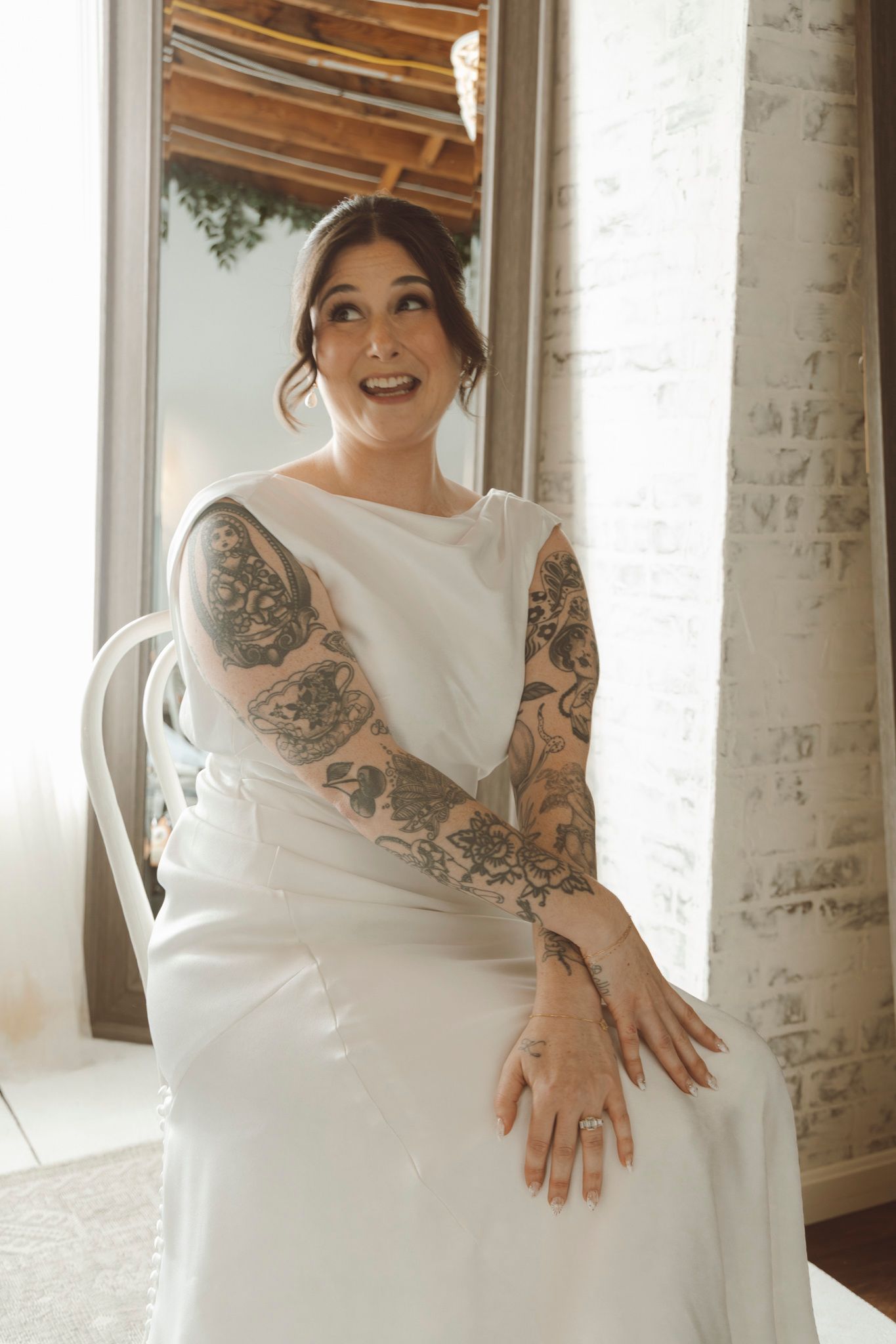Elegant white wedding dress showcasing intricate details and beautiful sleeve tattoo artwork.