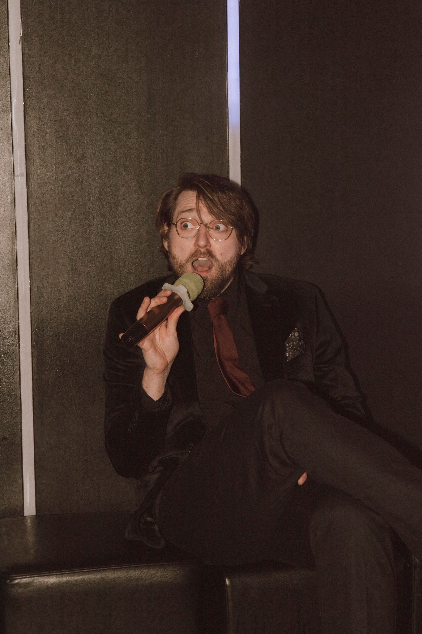Artist in black outfit performing passionately on stage with dramatic poses.