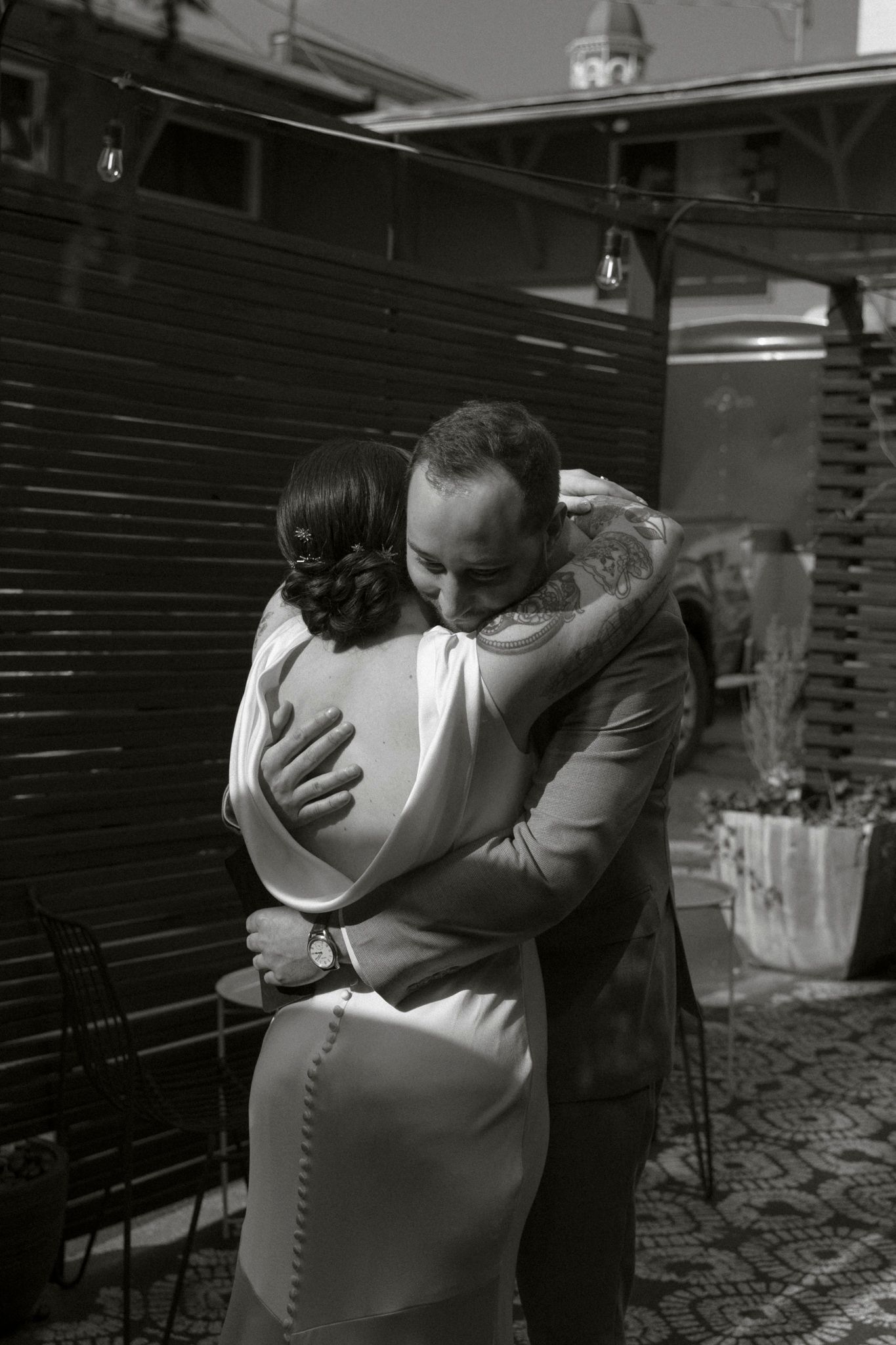 A black and white photo captures a tender embrace between newlyweds during their ceremony.