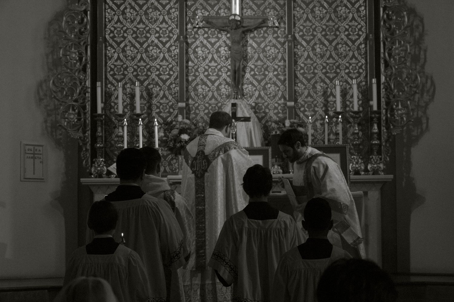 Priests and altar servers perform a traditional Catholic wedding Mass at an ornate altar.
