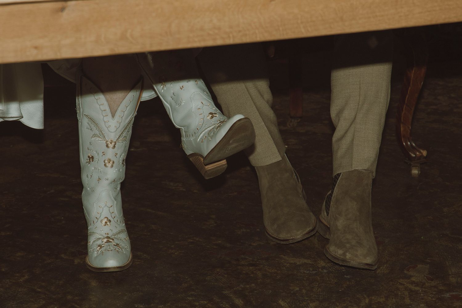Feet and legs of people dancing in a line on a dark wooden floor during a social gathering.