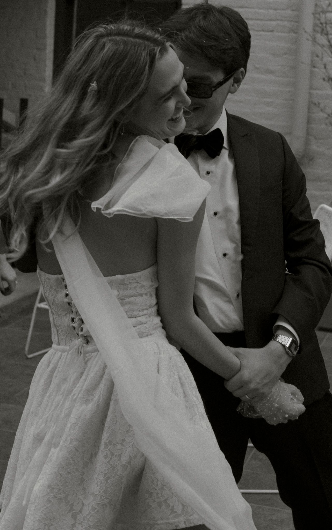 A black and white wedding photo series showing a bride and groom in romantic poses with her veil flowing.