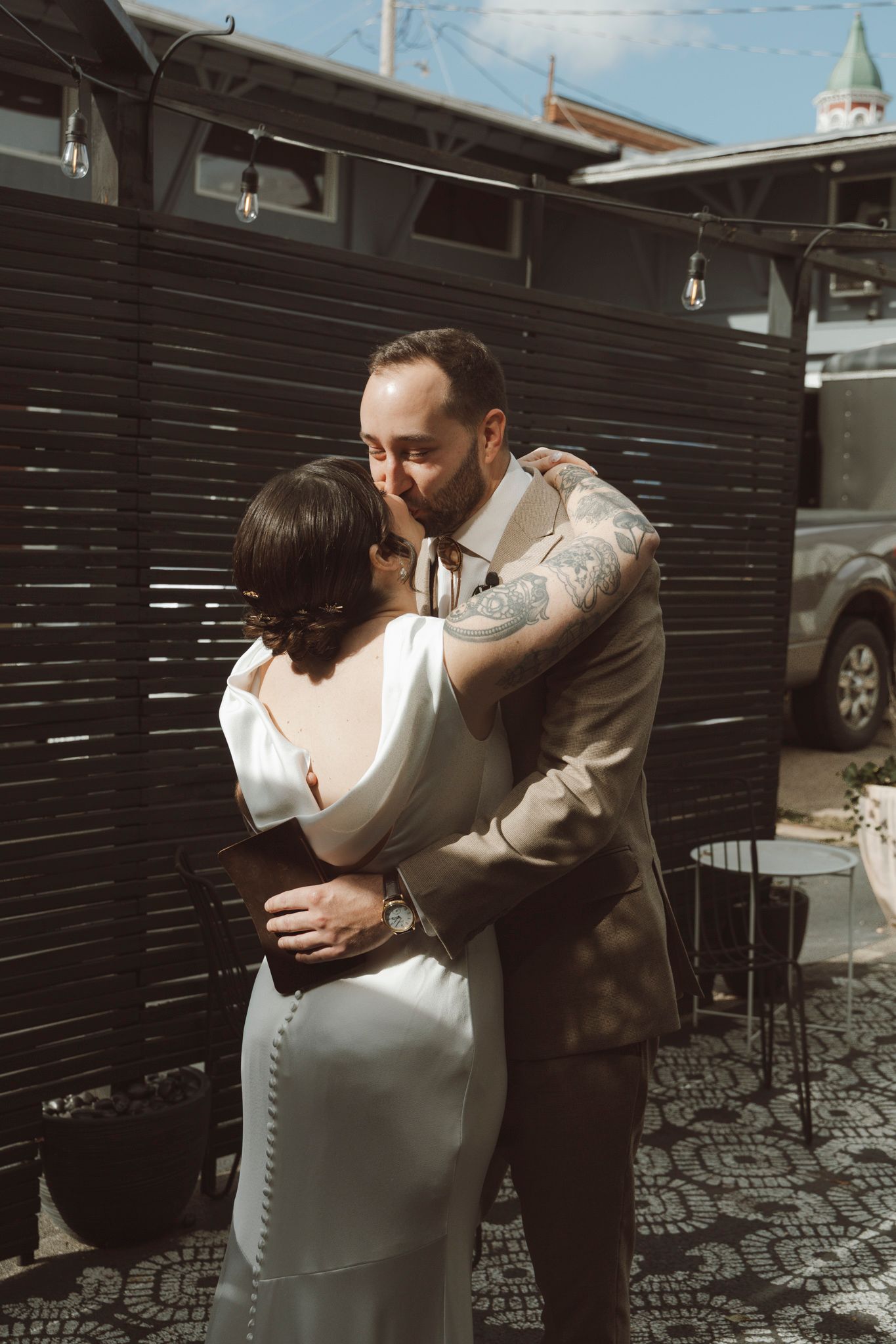 A sequence of intimate outdoor photos showing a couple embracing against a dark wooden wall background.