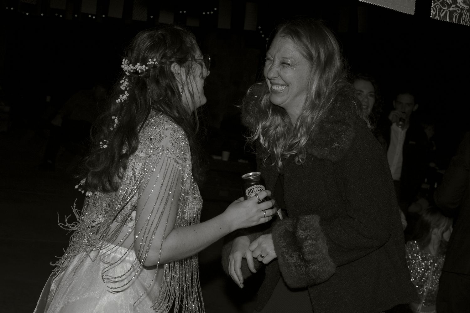Two people share a joyful moment dancing and laughing together at a social gathering in black and white.
