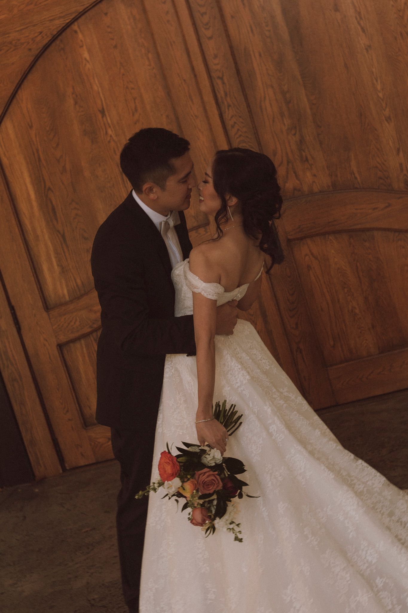 A romantic wedding moment captured against wooden doors with a beautiful bouquet.