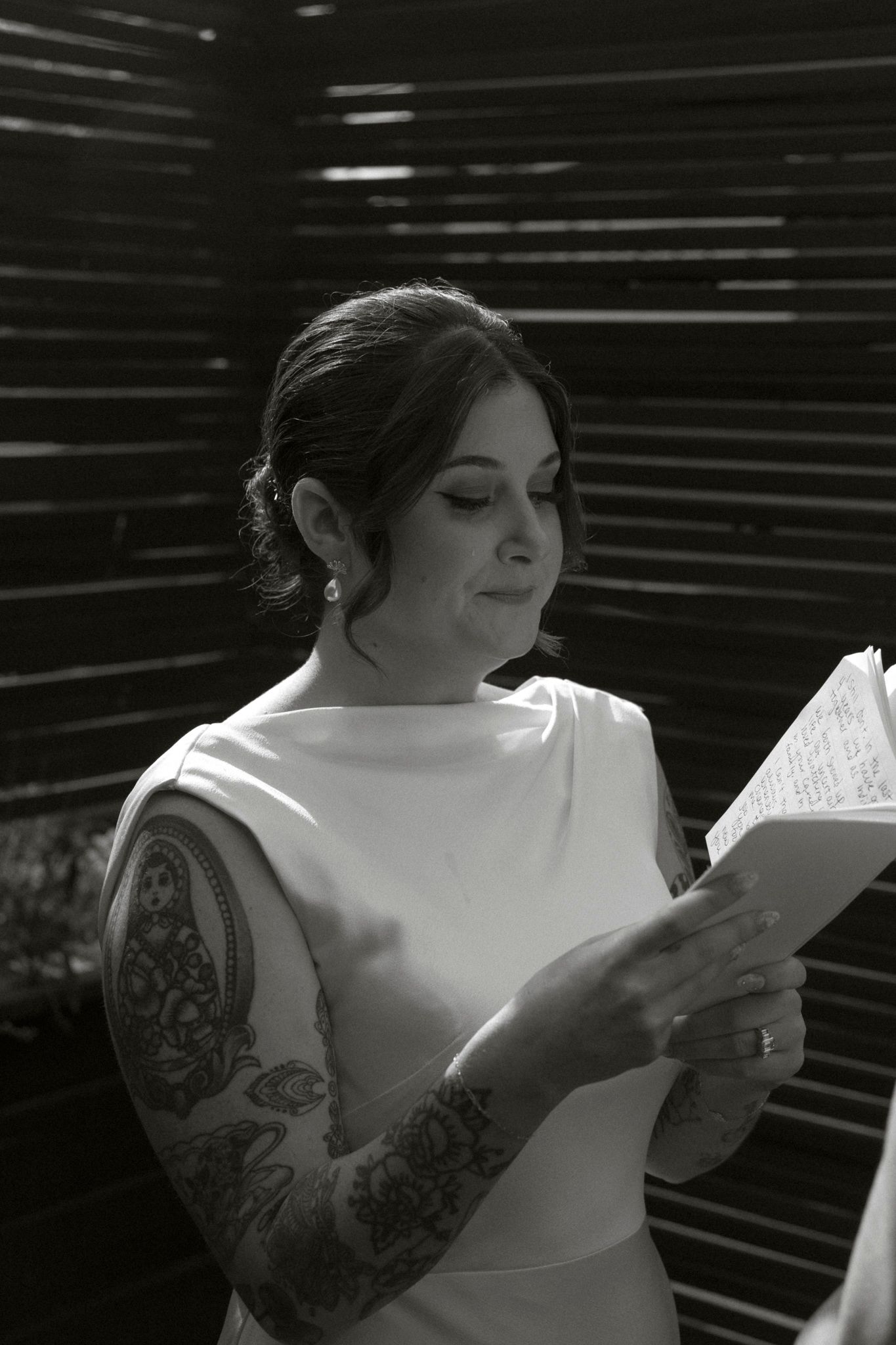 A series of black and white photos showing someone reading papers with visible arm tattoos in dramatic lighting.