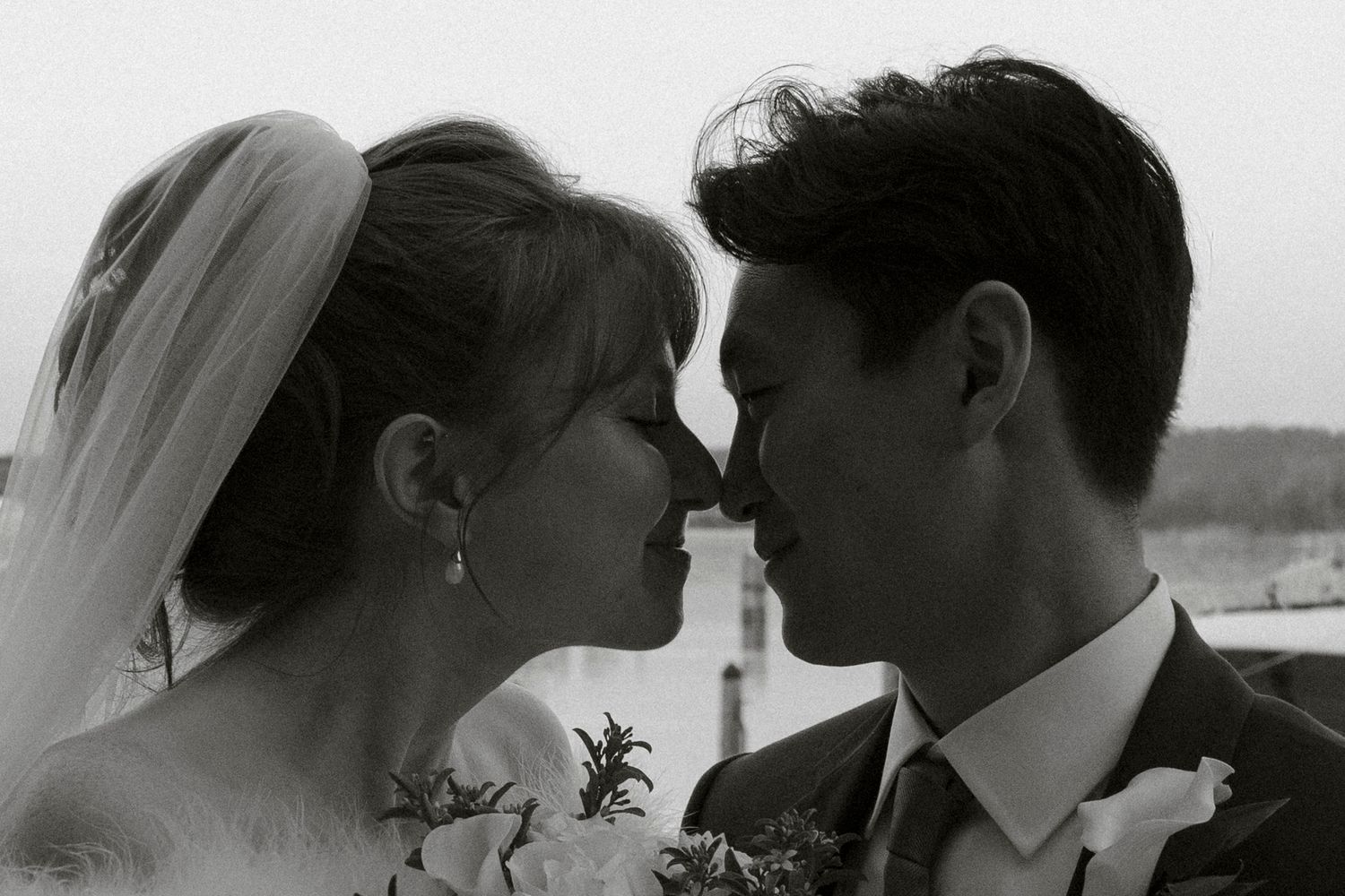 Black and white close-up of bride and groom touching foreheads tenderly on their wedding day.