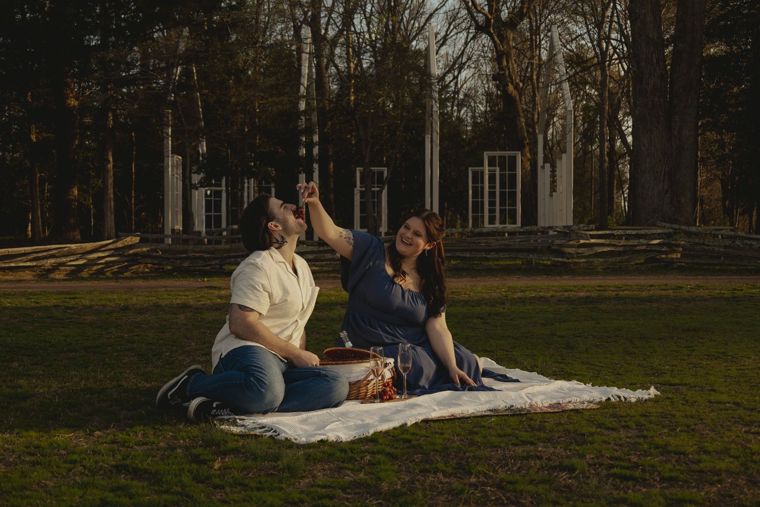 Happy couple sitting on a picnic blanket in a park, sharing a joyful moment at golden hour.