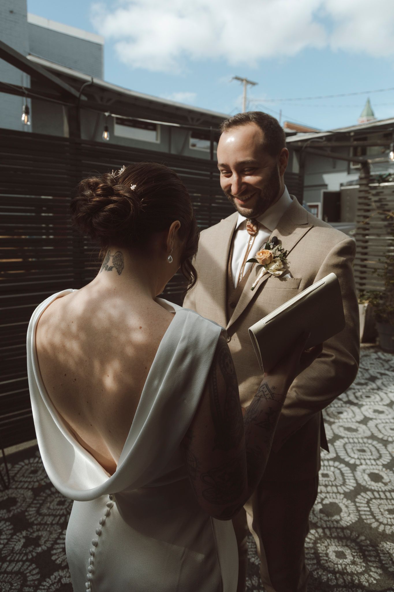 A couple shares an intimate moment during their wedding ceremony against a dark wooden backdrop.