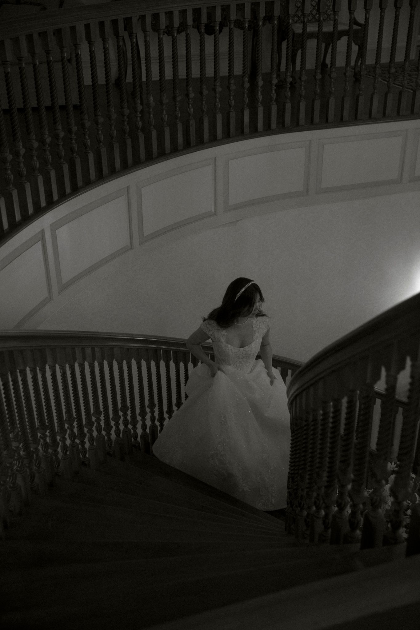 A sequence of dark images showing a person in a white dress descending a curved staircase in dramatic lighting.