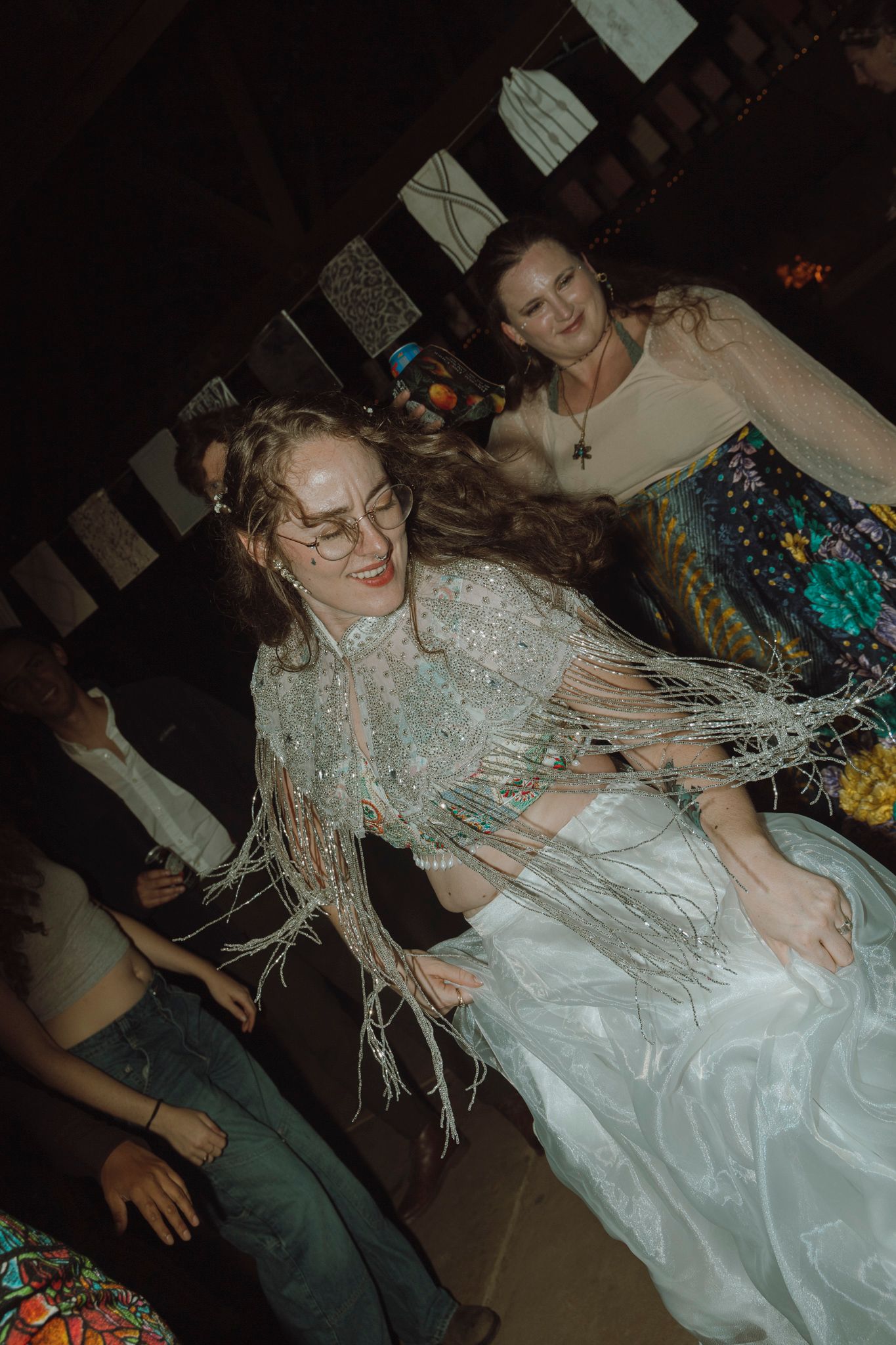 A sequence of party photos showing someone in a white dress dancing energetically with tinsel in their hair at a celebration.