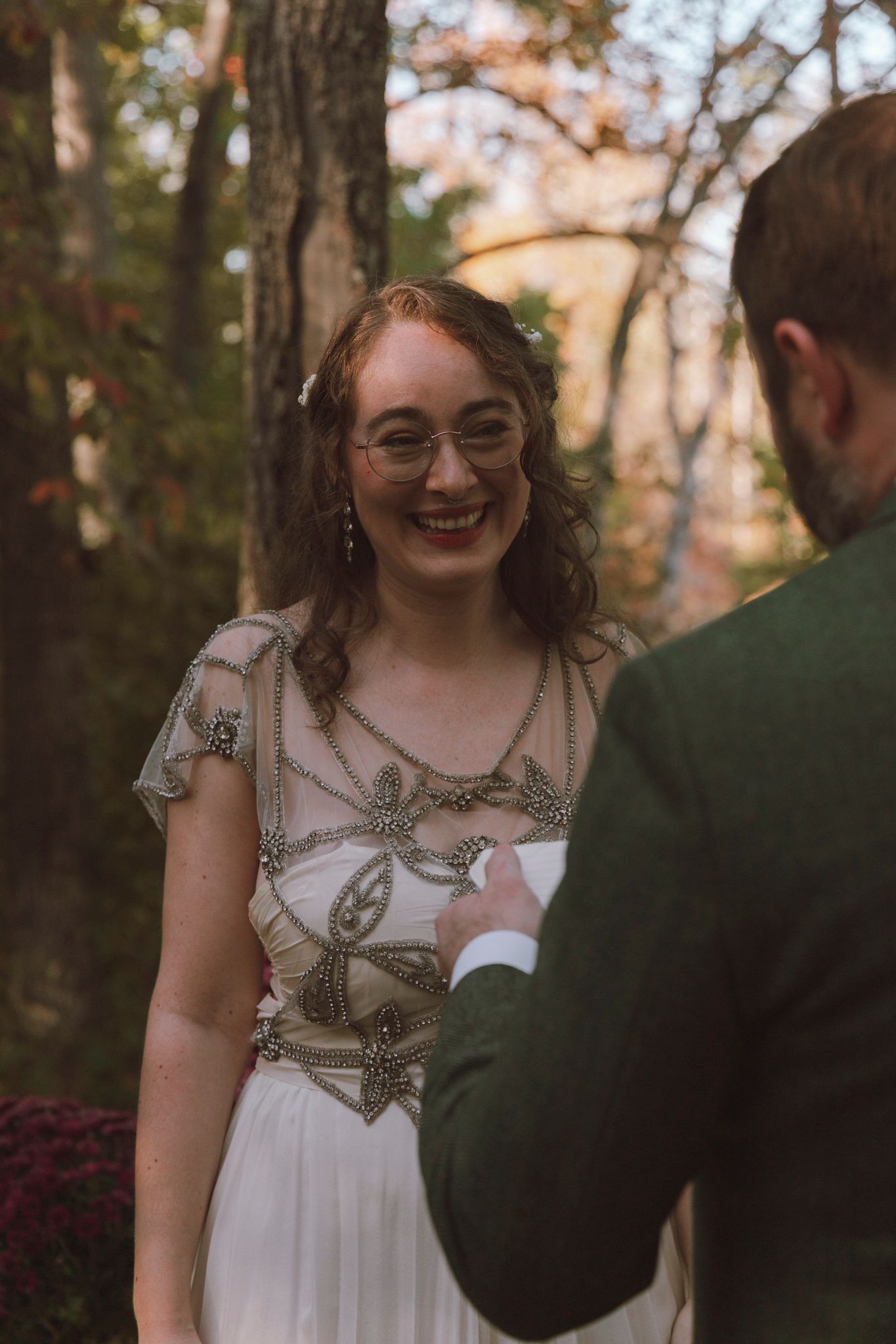 A couple shares a joyful moment together in an outdoor autumn setting with trees in the background.