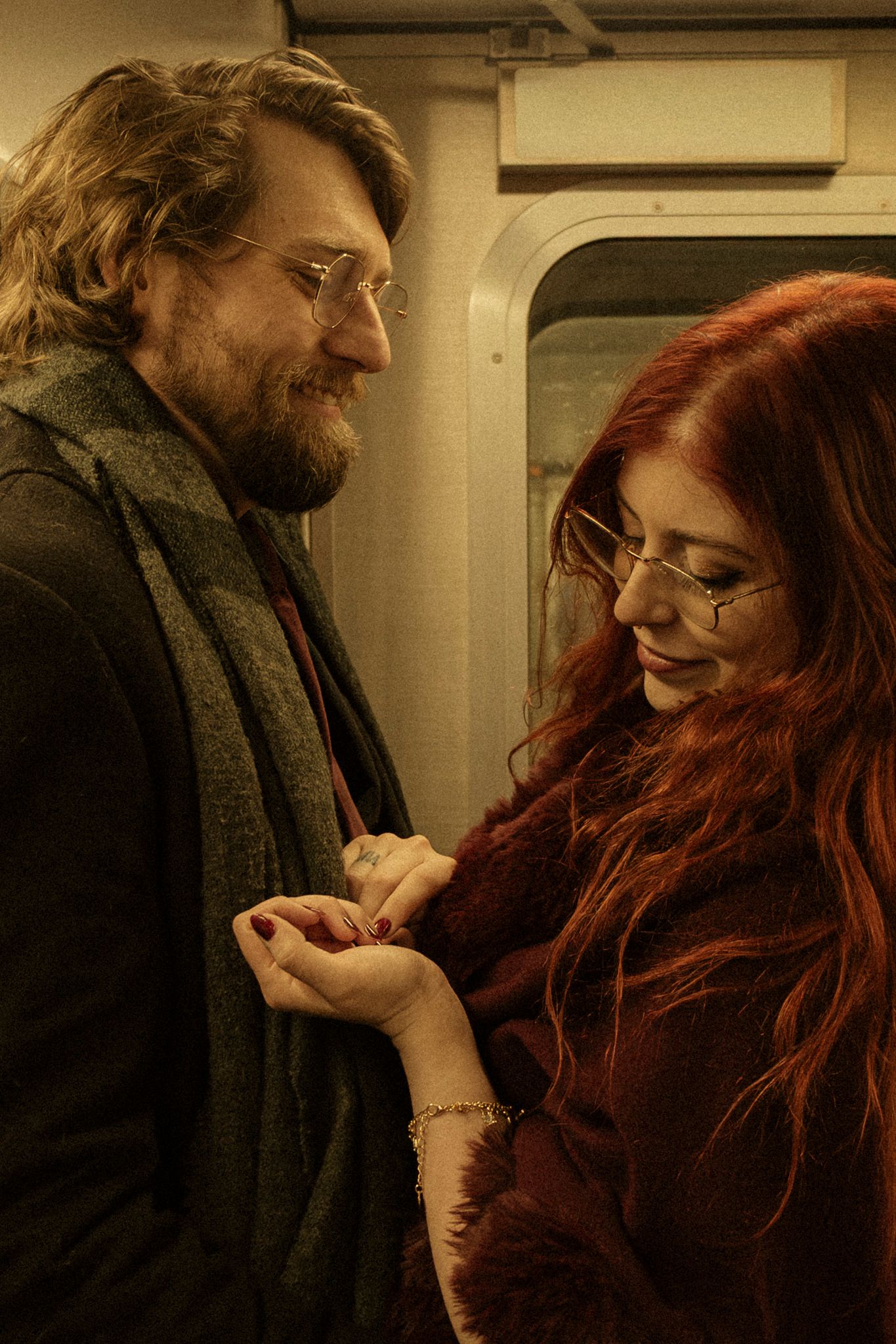 Two people share an intimate moment while standing together on public transit.