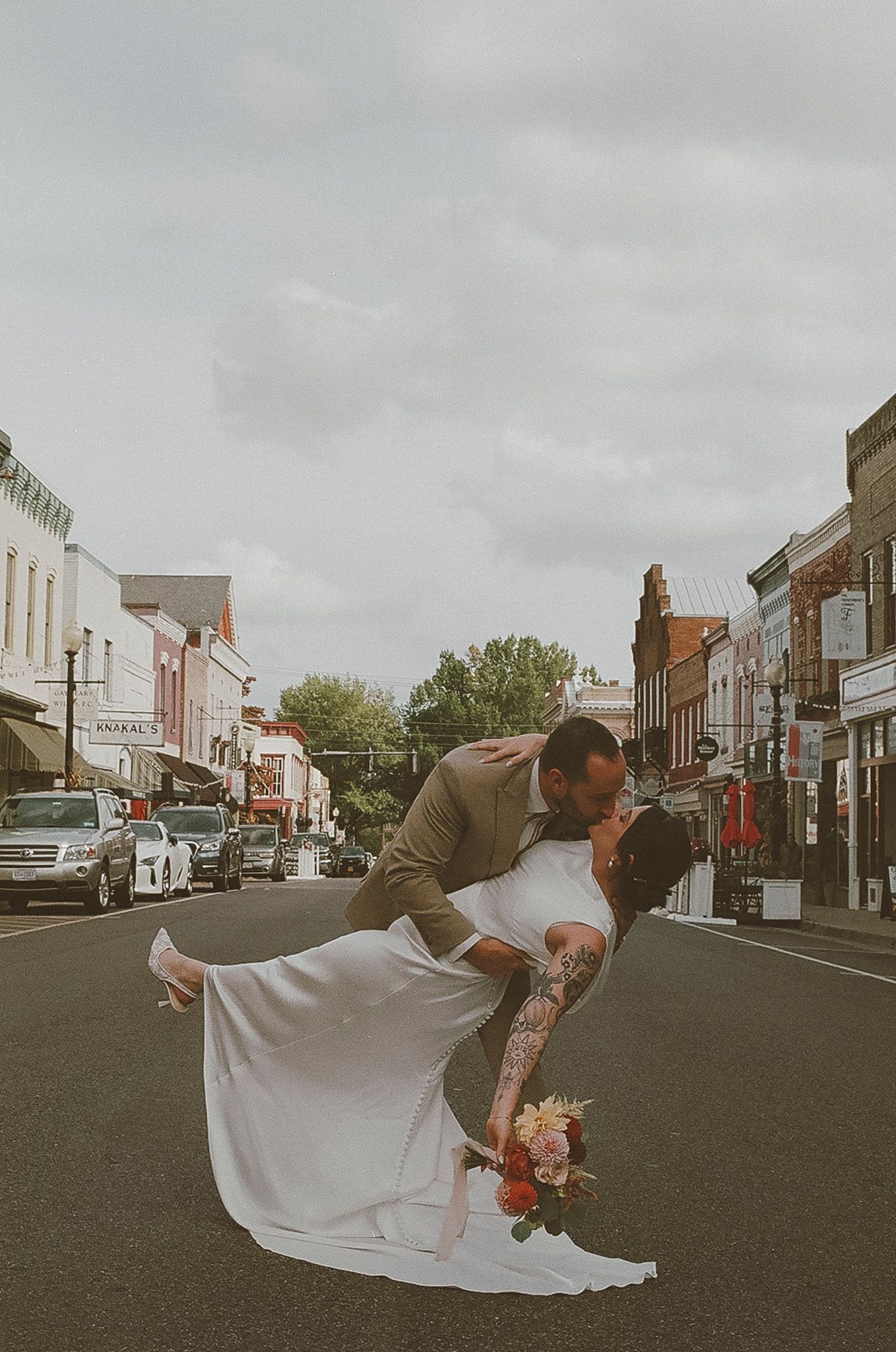 Romantic wedding dip pose in the middle of a charming small town street with vintage storefronts in background.