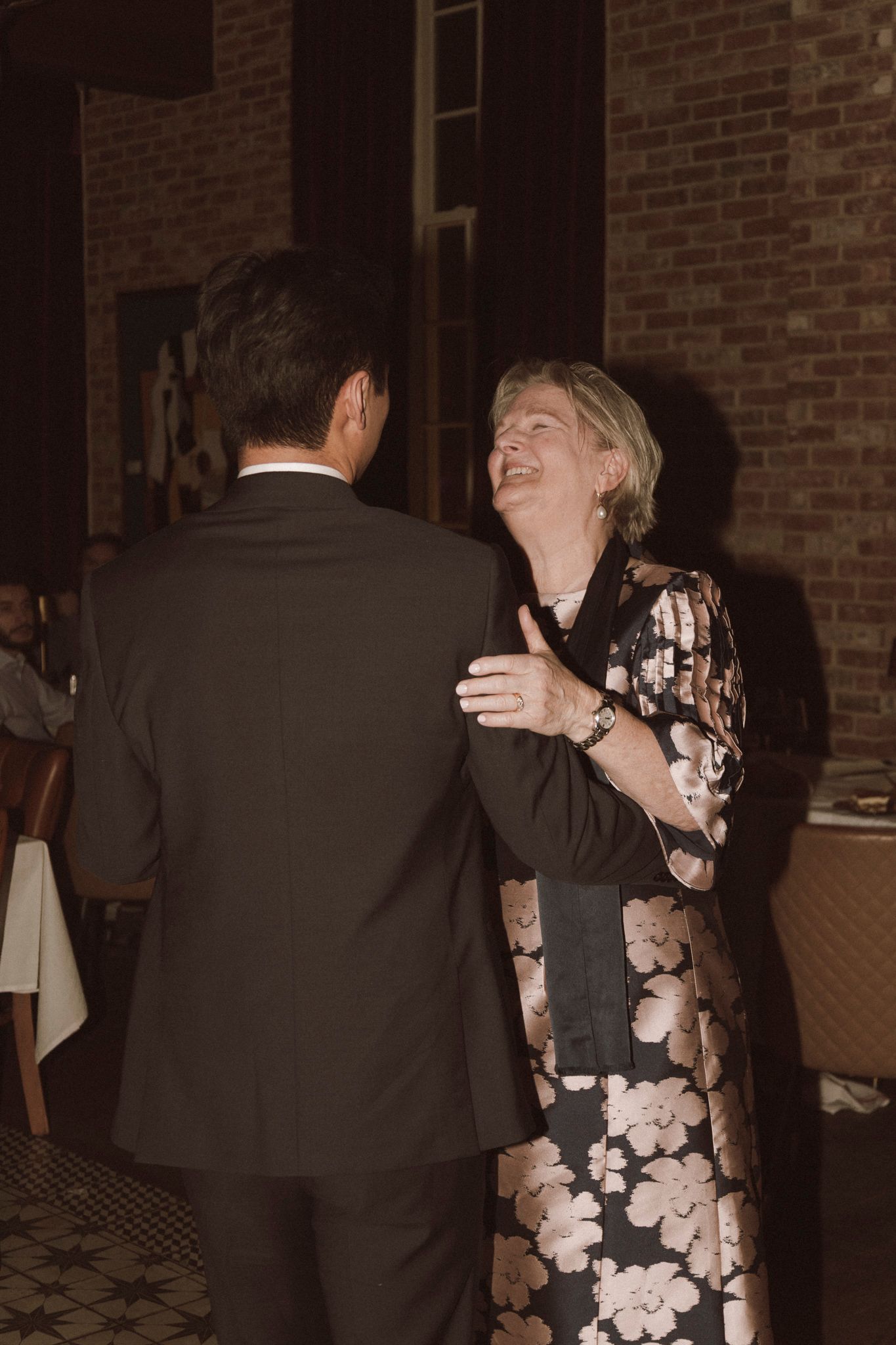 Elegant couple dancing and laughing together at a formal indoor reception event.