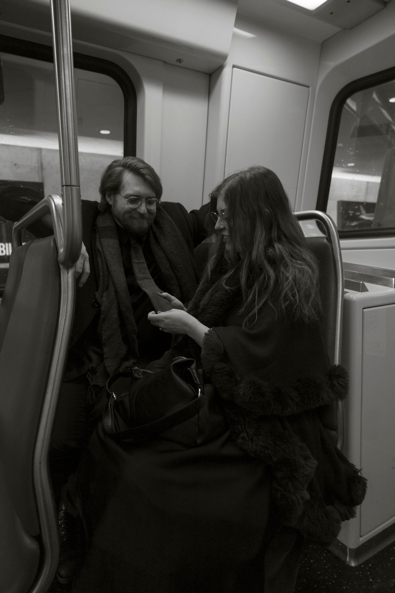 Four sequential black and white photos show people embracing and hugging in what appears to be a subway car interior.