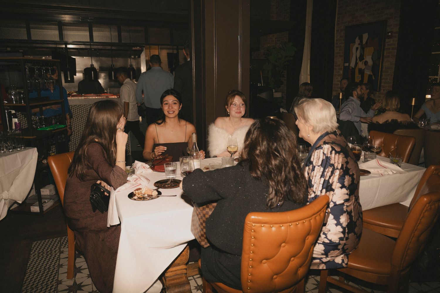 Wedding guests gathered around a dining table sharing conversation during a formal reception dinner.