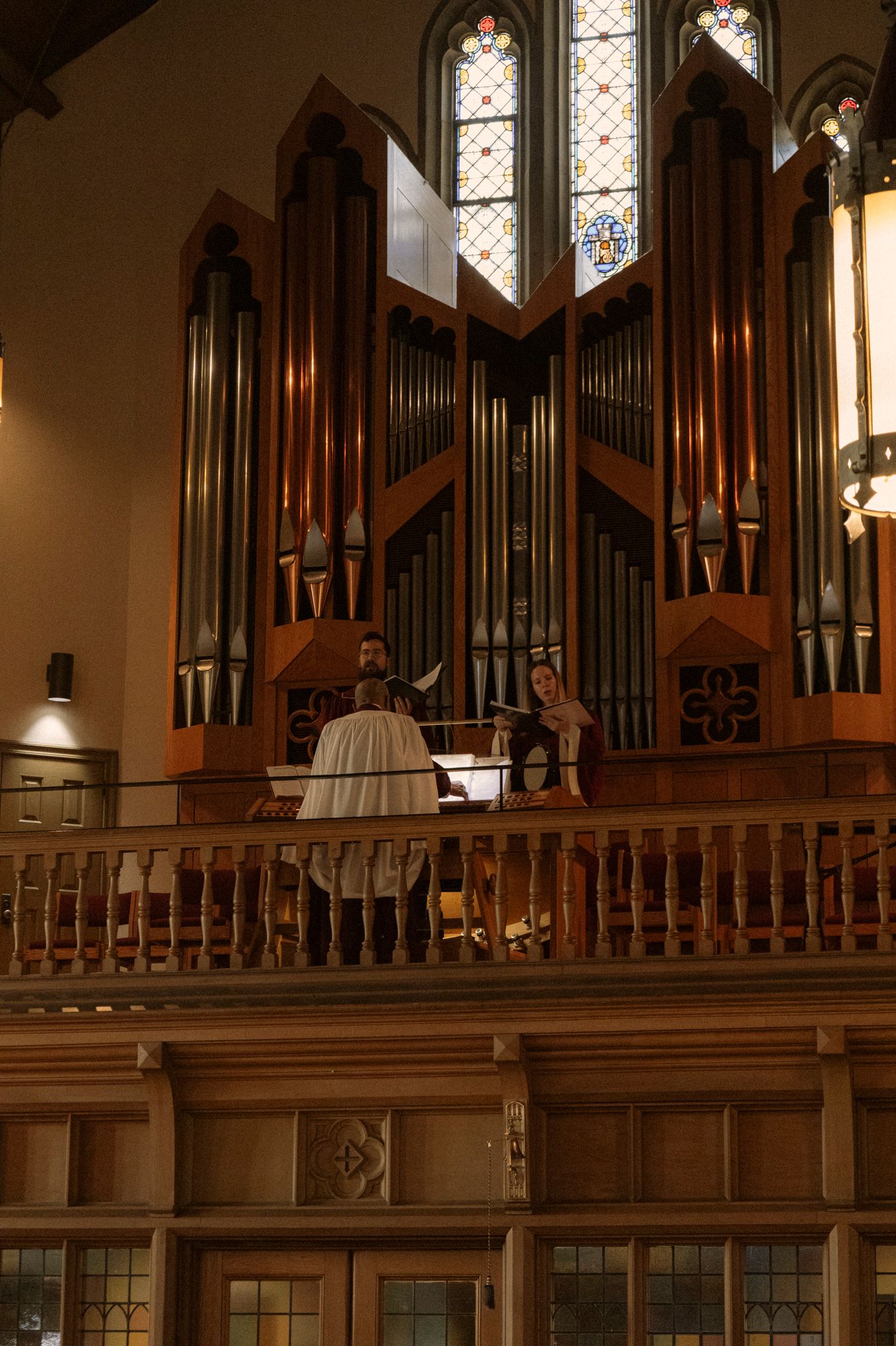 Organist performing on a grand pipe organ in the choir loft of a historic church during a wedding.