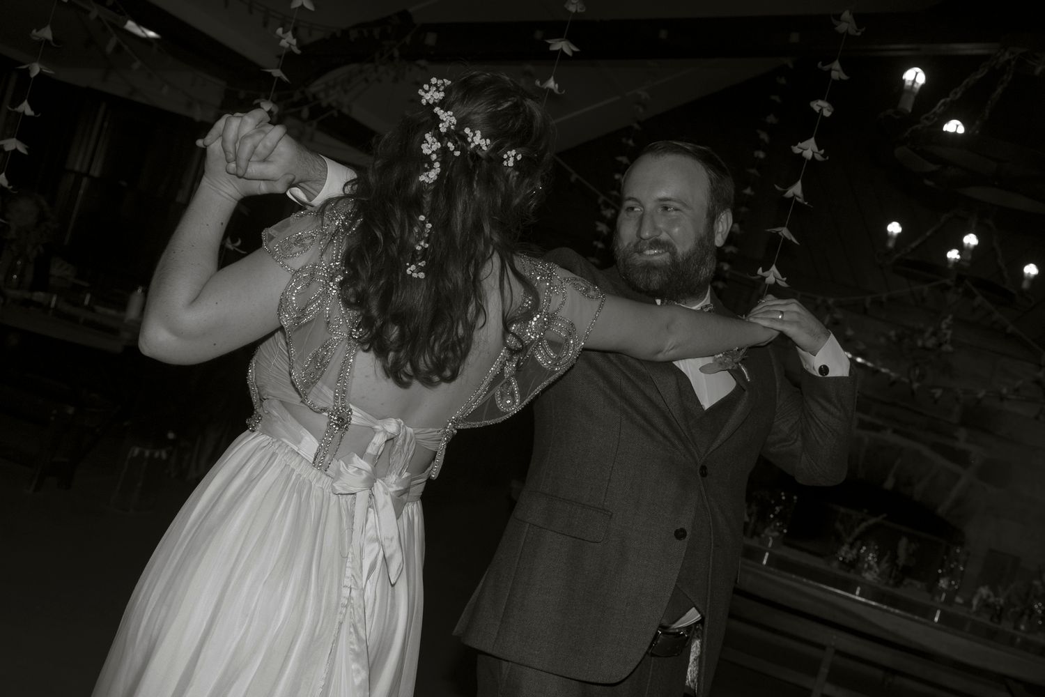 Wedding couple and guests dance and celebrate on a dimly lit dance floor during an evening reception.