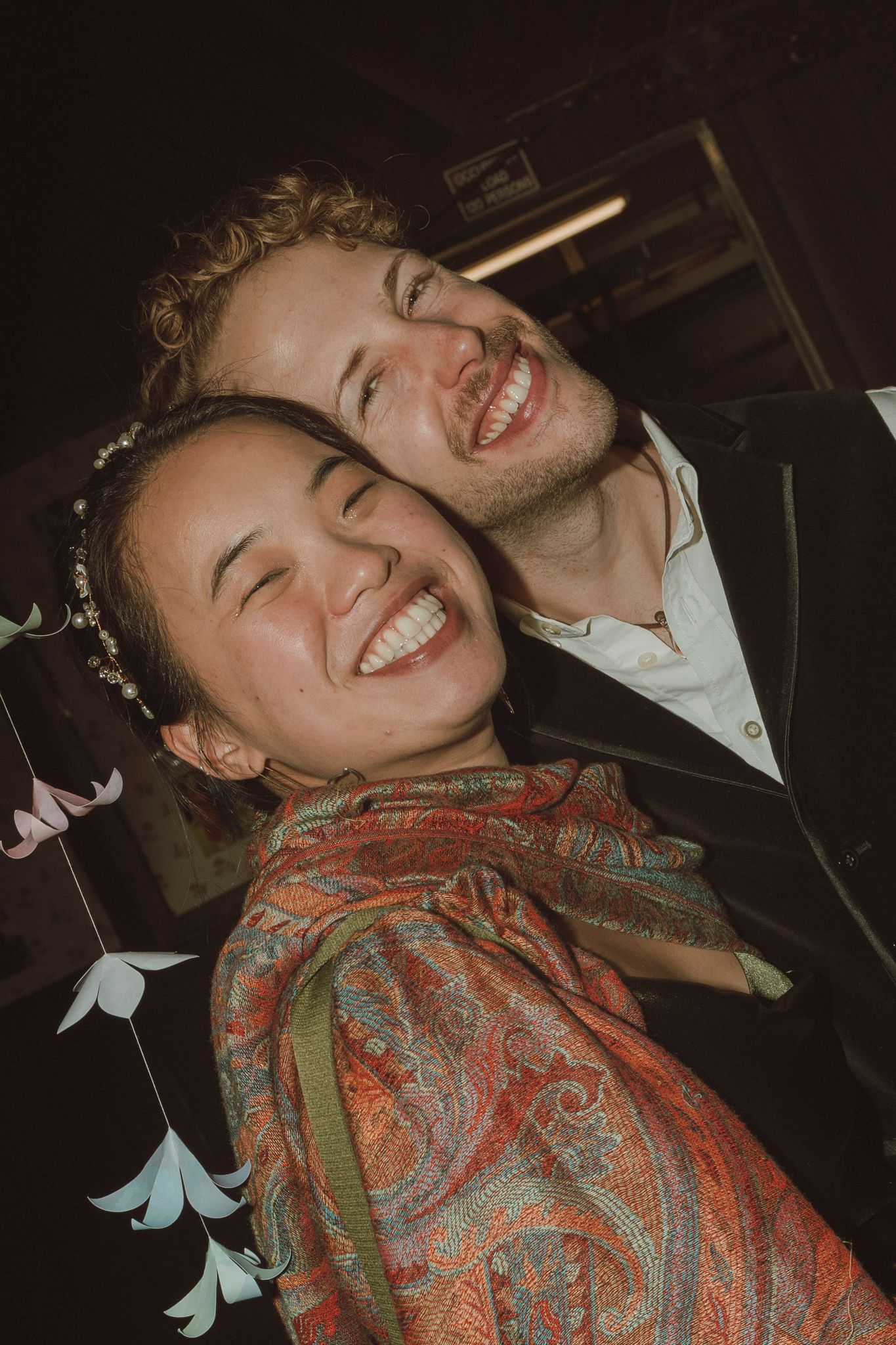 A candid series of joyful expressions showing someone laughing while wearing a patterned paisley scarf in dim lighting.