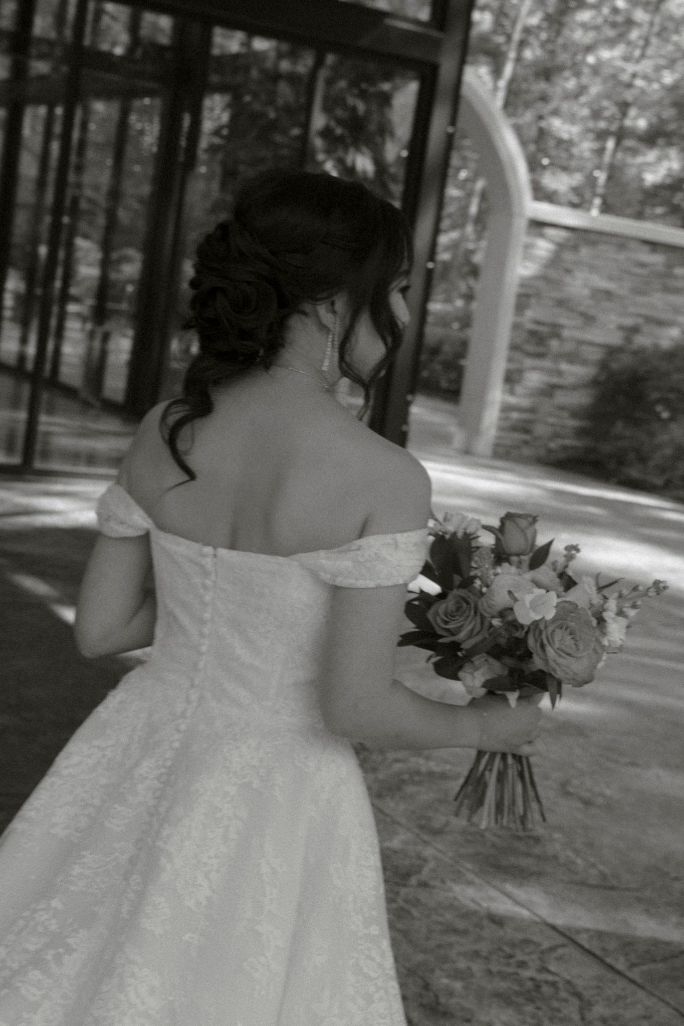 Black and white photo series showing close-up details of a white wedding dress with floral accents and off-shoulder design.