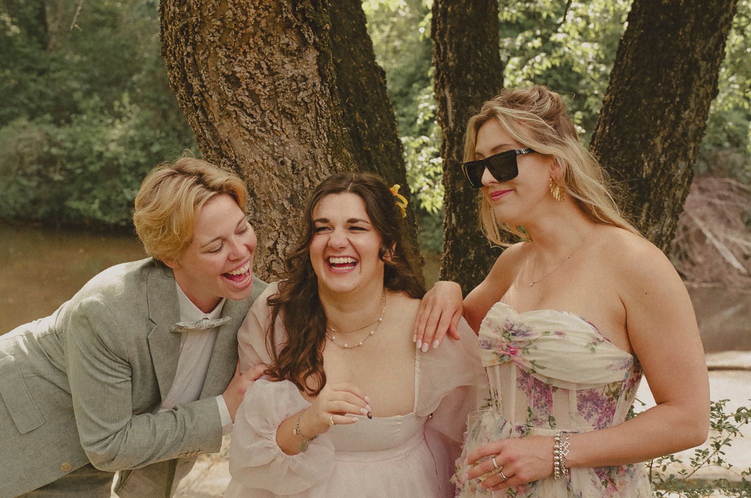 A romantic wedding couple shares intimate moments in a wooded outdoor setting with natural lighting and trees.