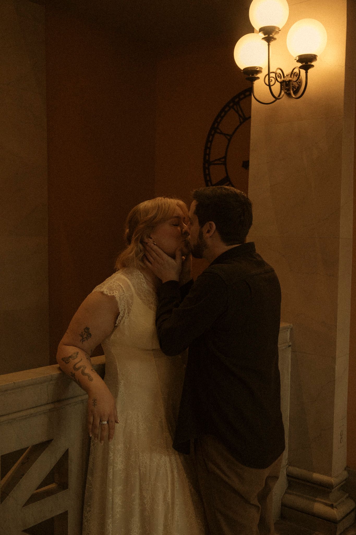 A couple shares an intimate dance moment in a dimly lit hallway with warm lighting and elegant wall sconces.