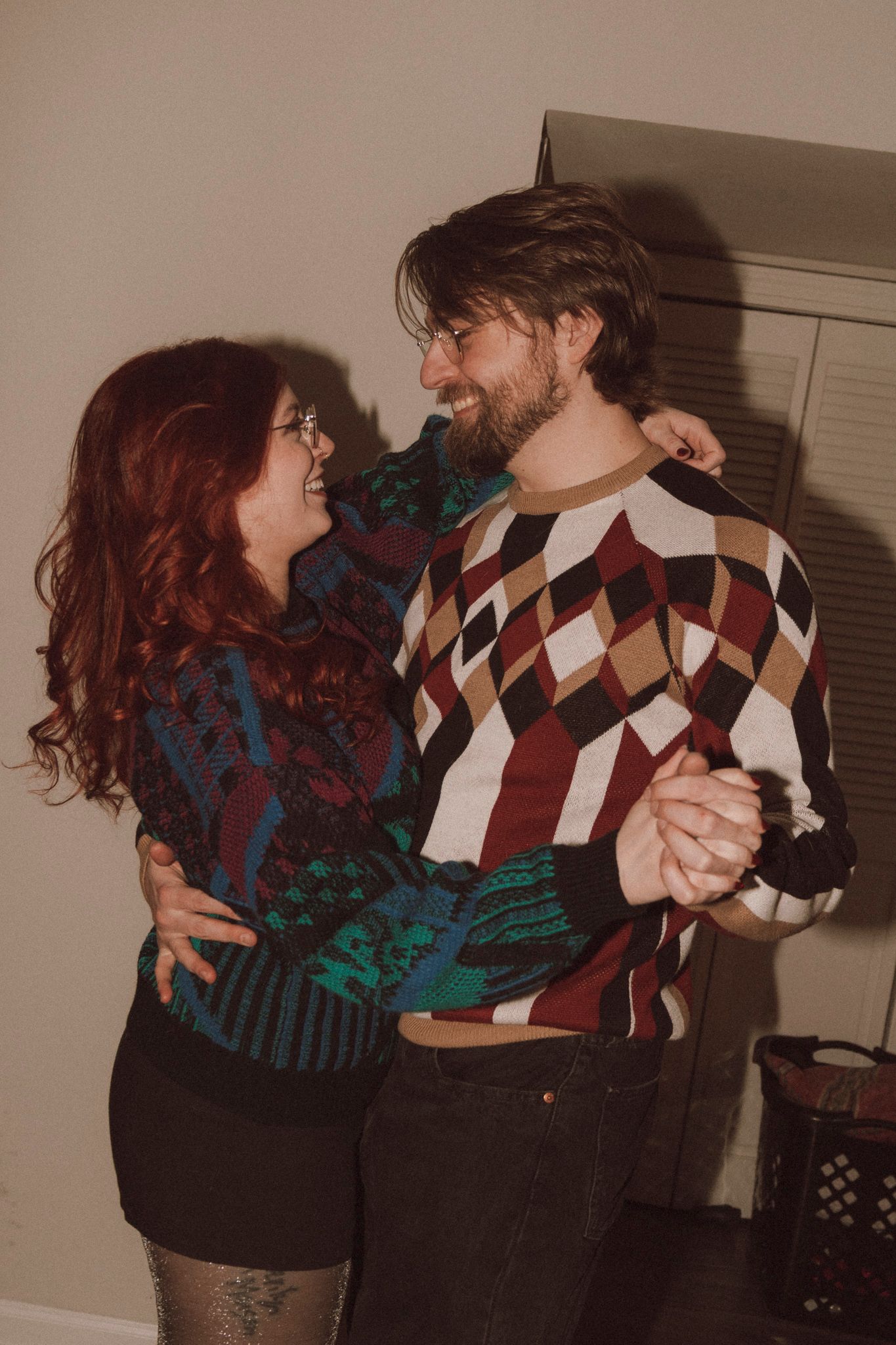 Couple dancing together indoors wearing vintage patterned sweaters.