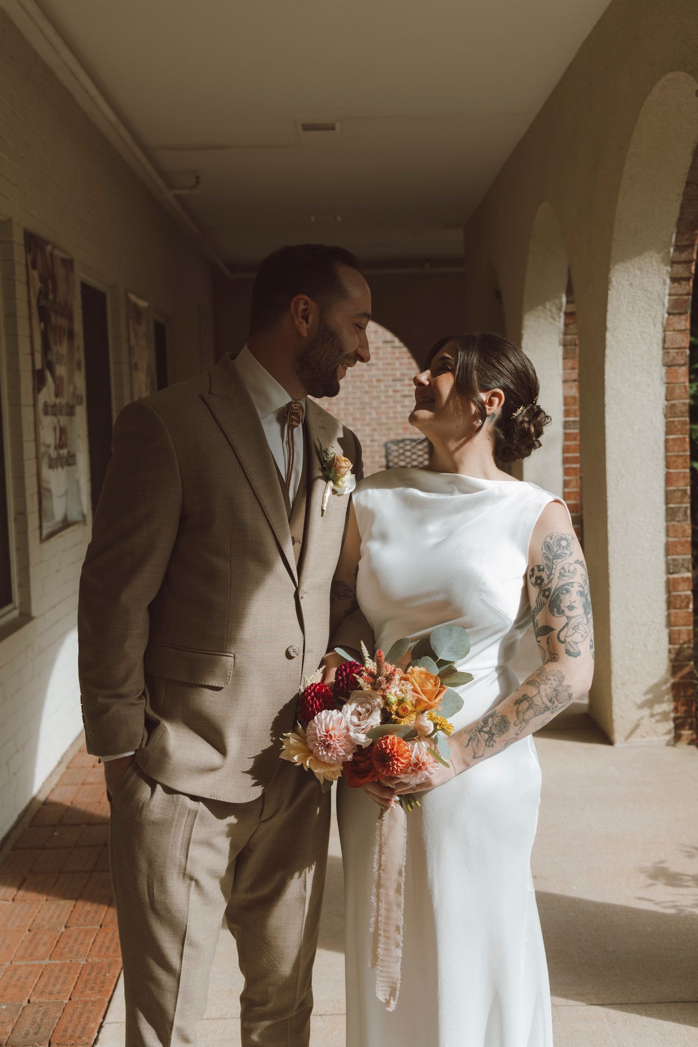 A couple shares an intimate moment in a brick-lined hallway during their wedding.