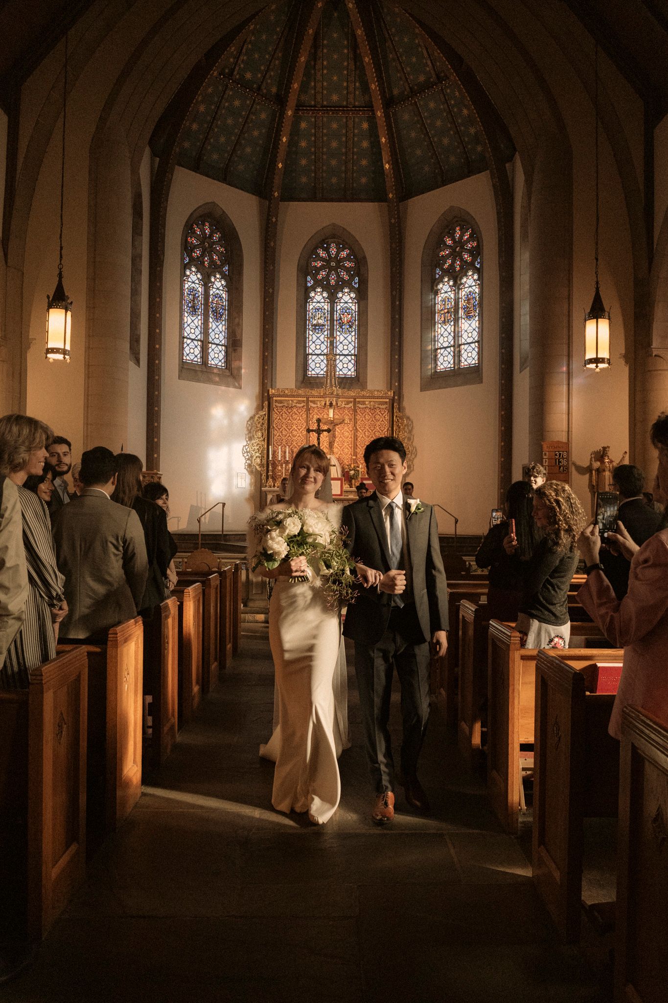 Newlyweds walk down the aisle of a stunning Gothic church after their wedding ceremony.