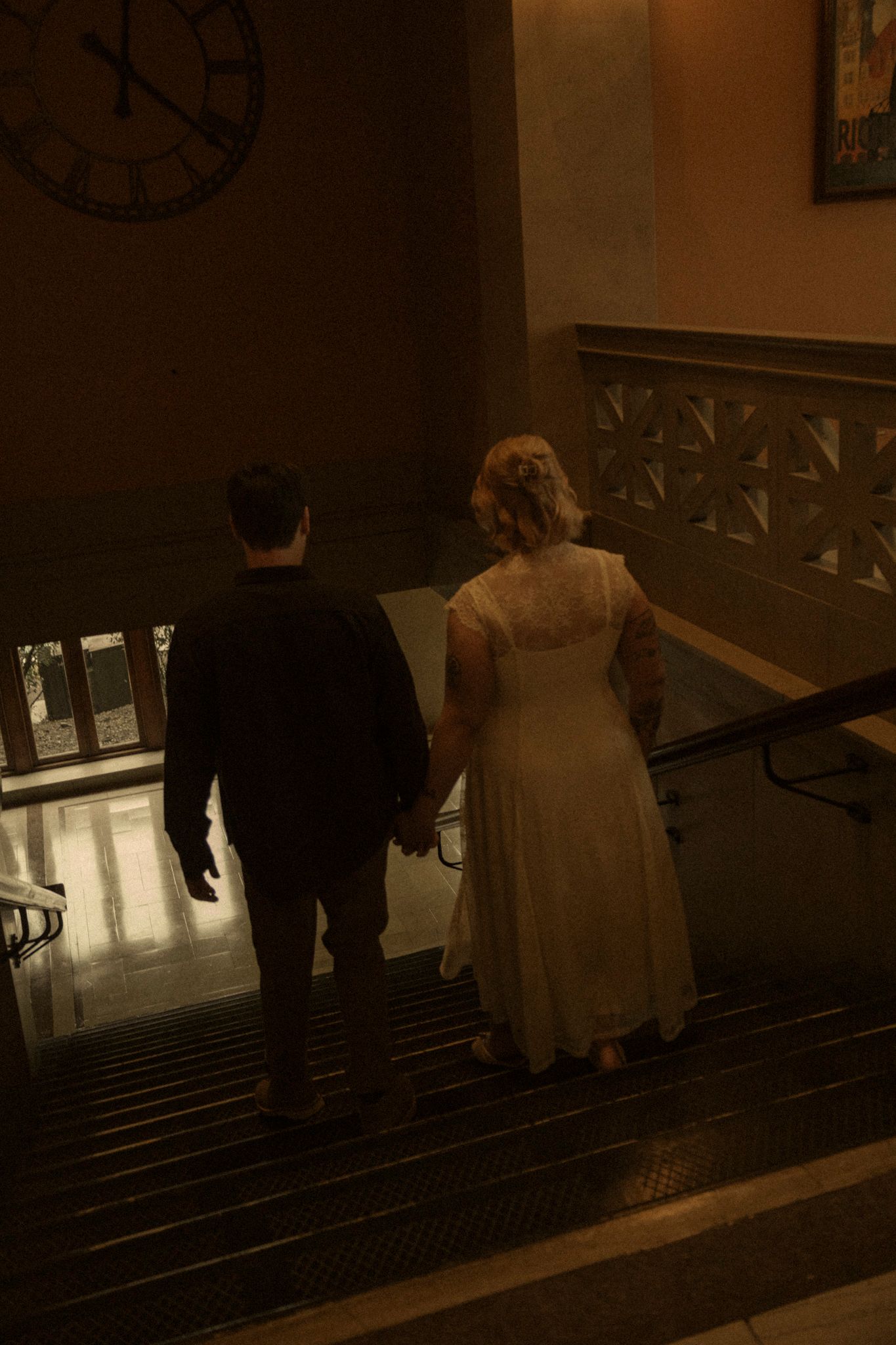 People descending a dark staircase in what appears to be an old building with vintage architectural details.