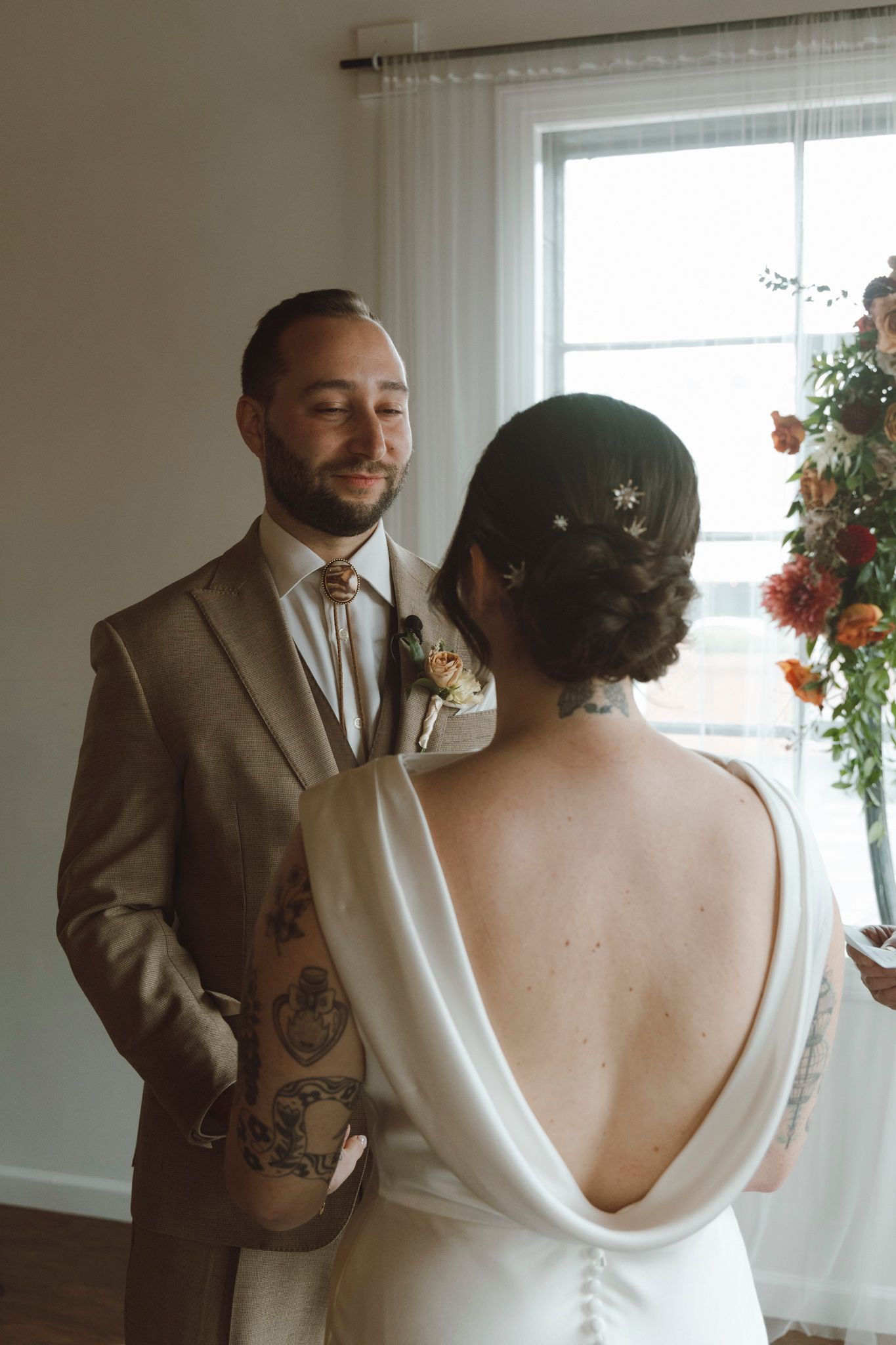 A tender first look moment between a couple on their wedding day in a bright indoor setting.