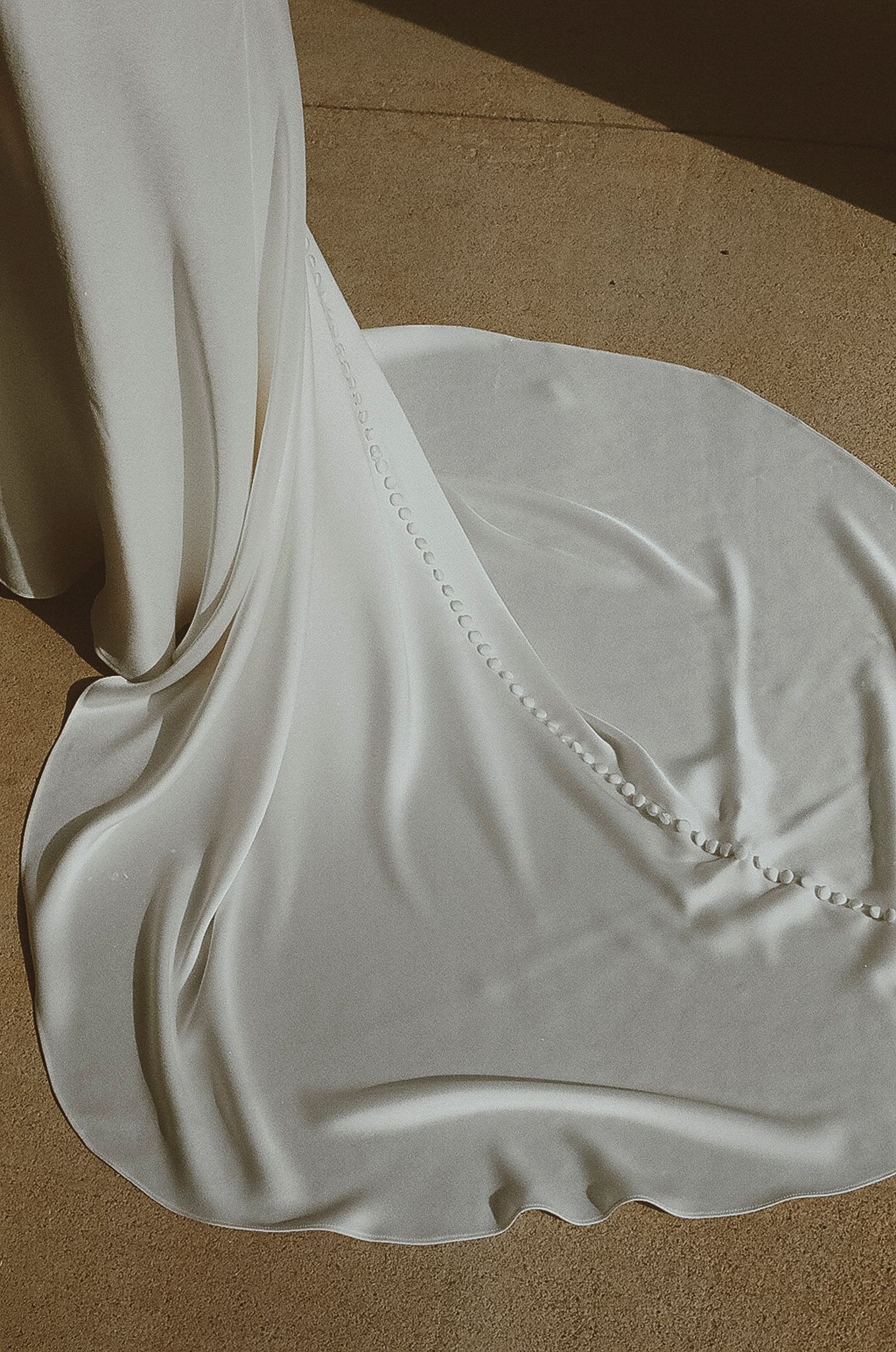 Close-up detail of a white wedding dress train with delicate button details.