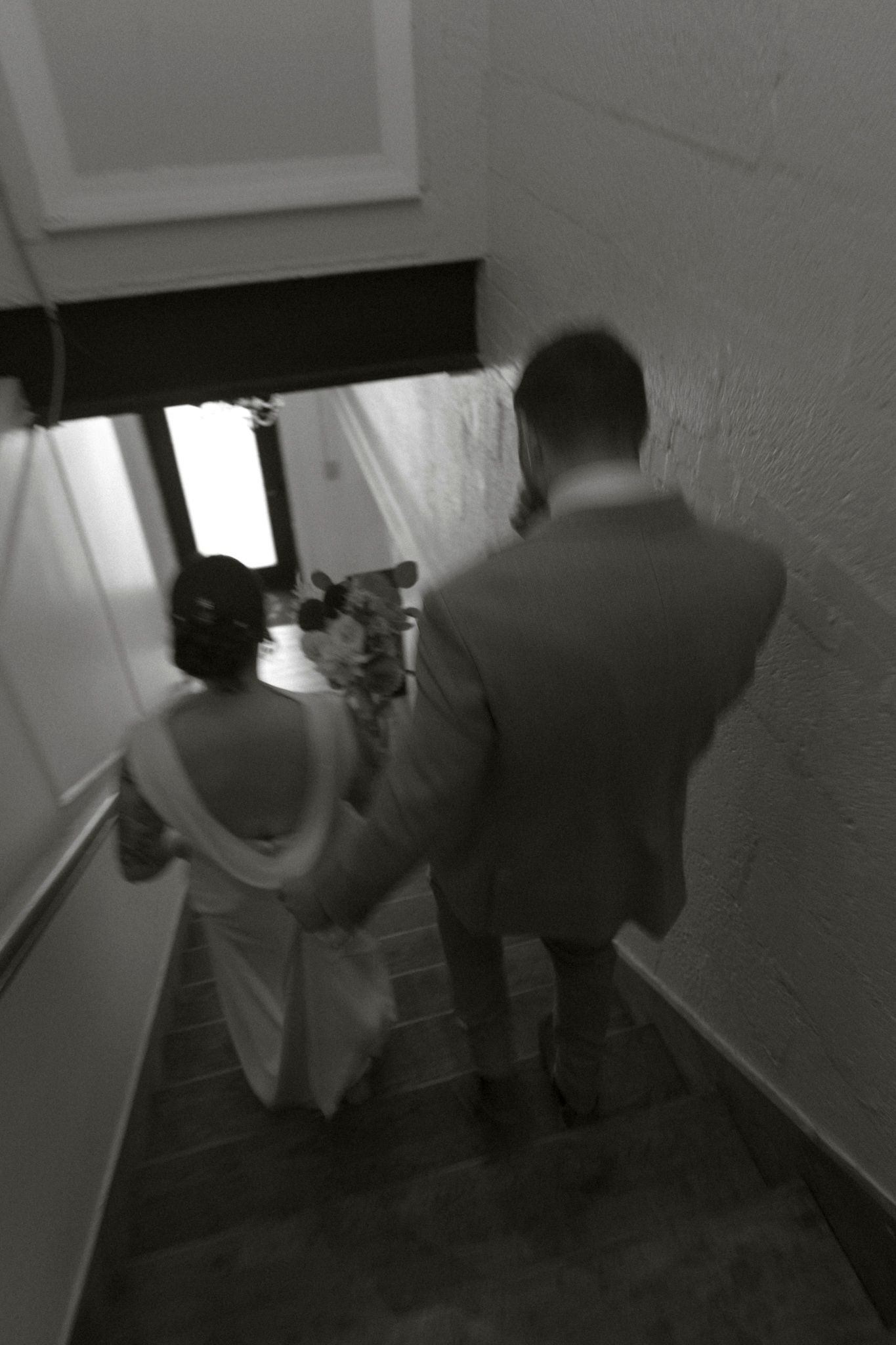 Two figures walk down a dark hallway in a sequence of surveillance camera-style black and white images.