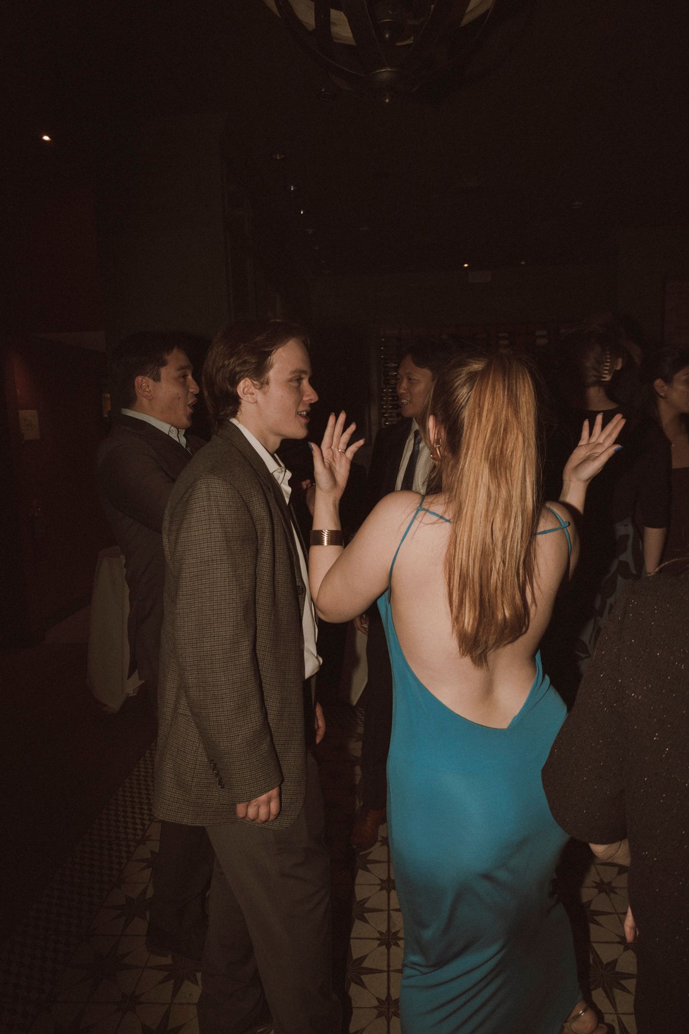 Guests dancing at elegant wedding reception, woman in teal satin dress on dance floor.
