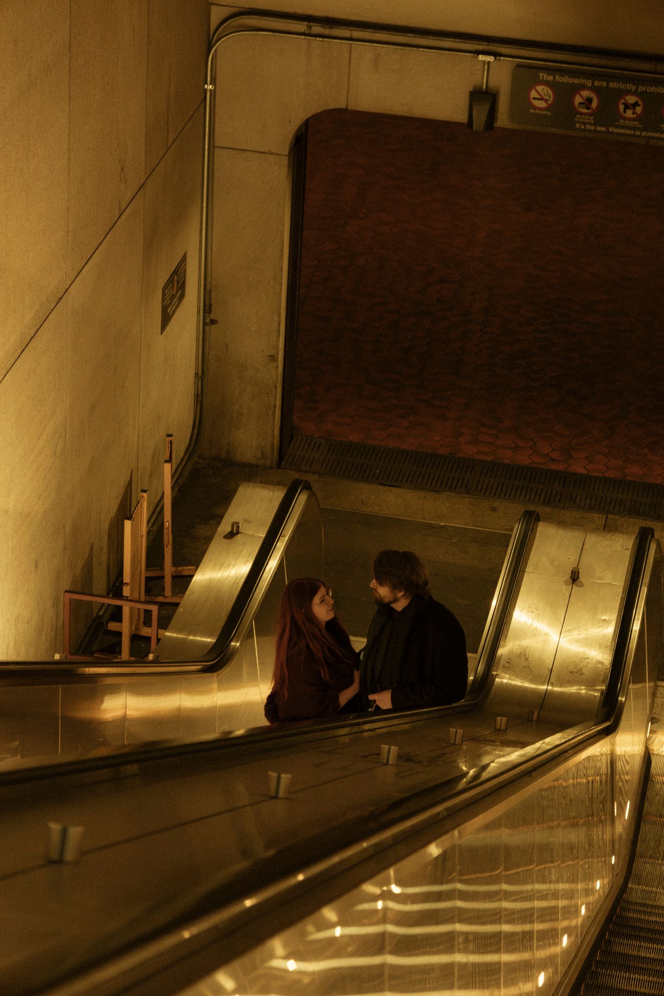A long, dimly lit escalator in a subway station casts dramatic shadows and creates an atmospheric mood.