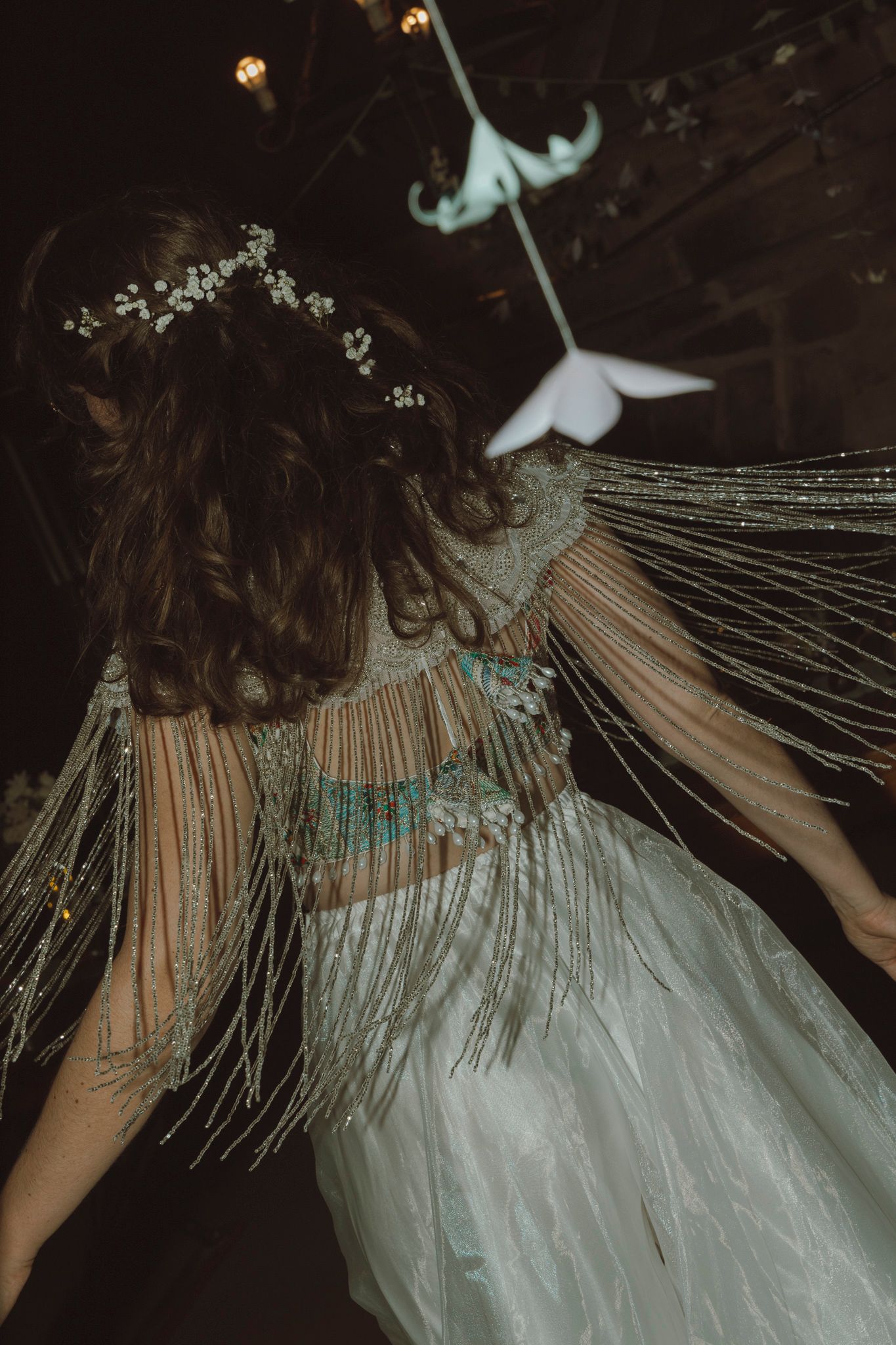 A series of ethereal photos showing flowing white fabric with delicate string details against a dark background.