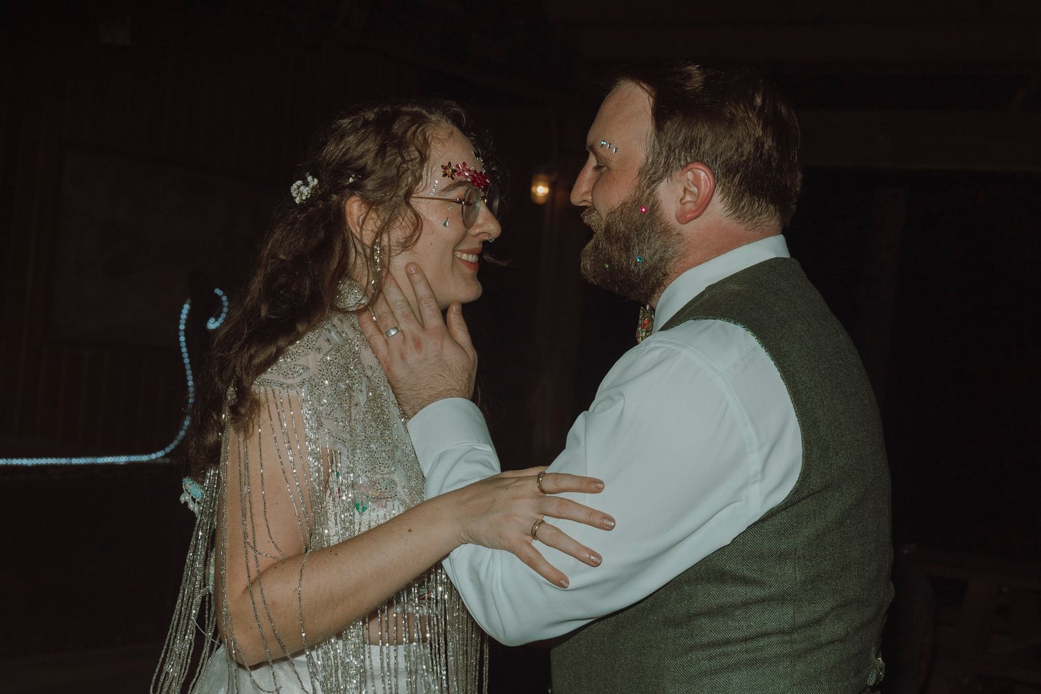A couple shares a romantic dance at their wedding reception in a dimly lit venue.