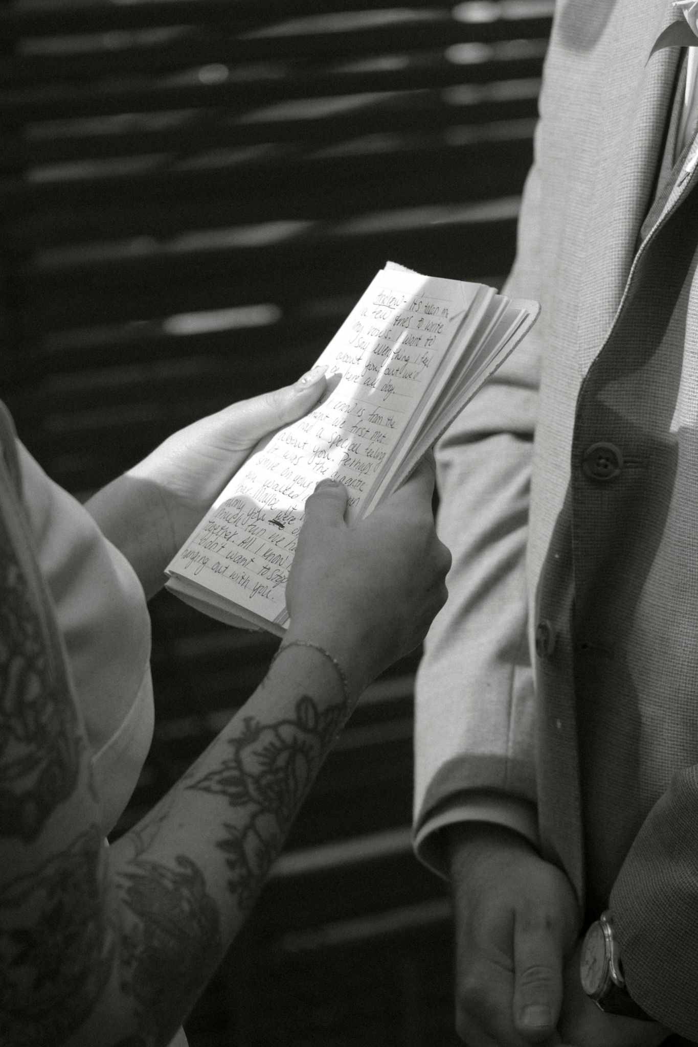 Close-up of hands holding wedding vows written in a small book during ceremony.