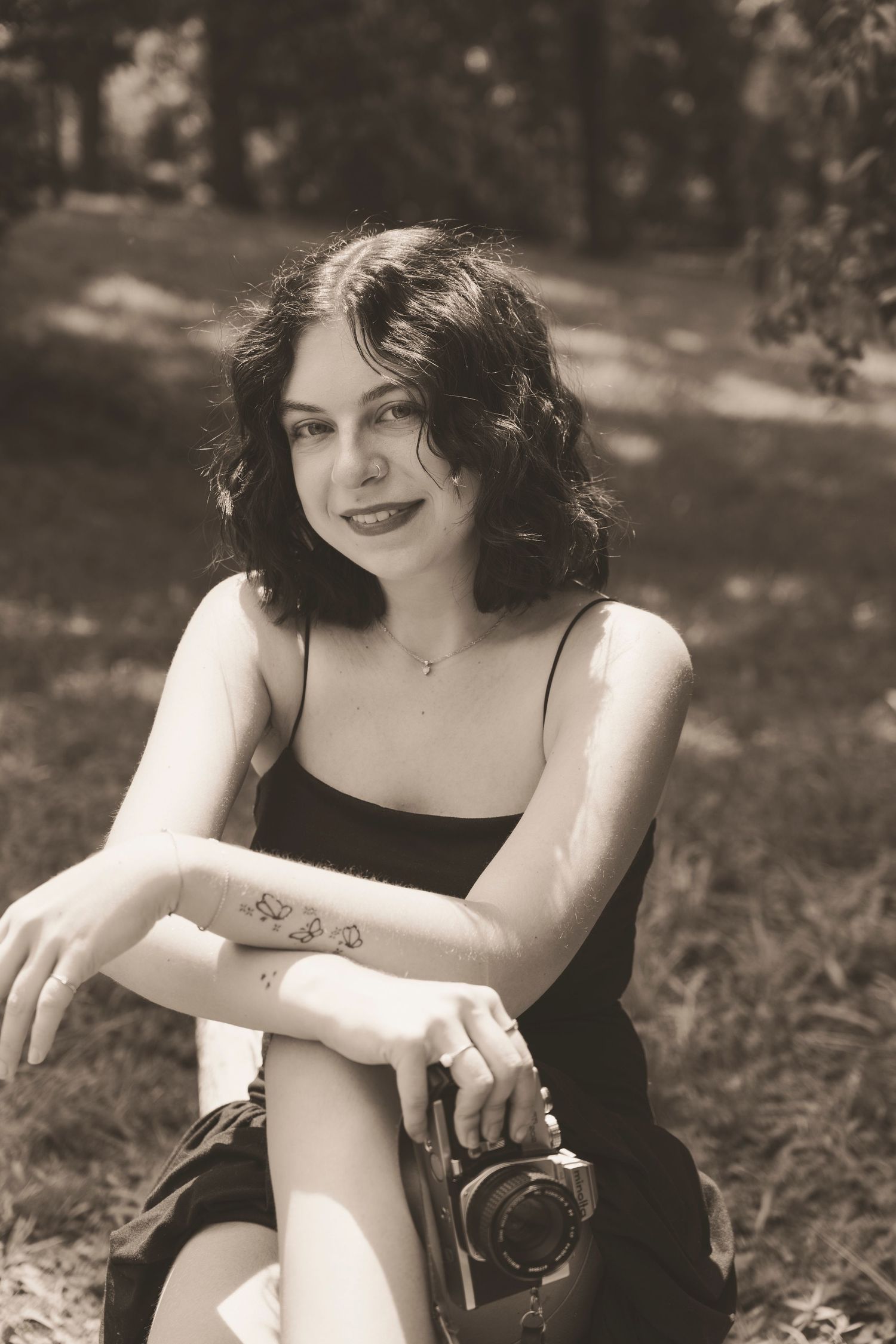 Vintage black and white photo of someone sitting outdoors in a black dress, captured in a series of similar poses.